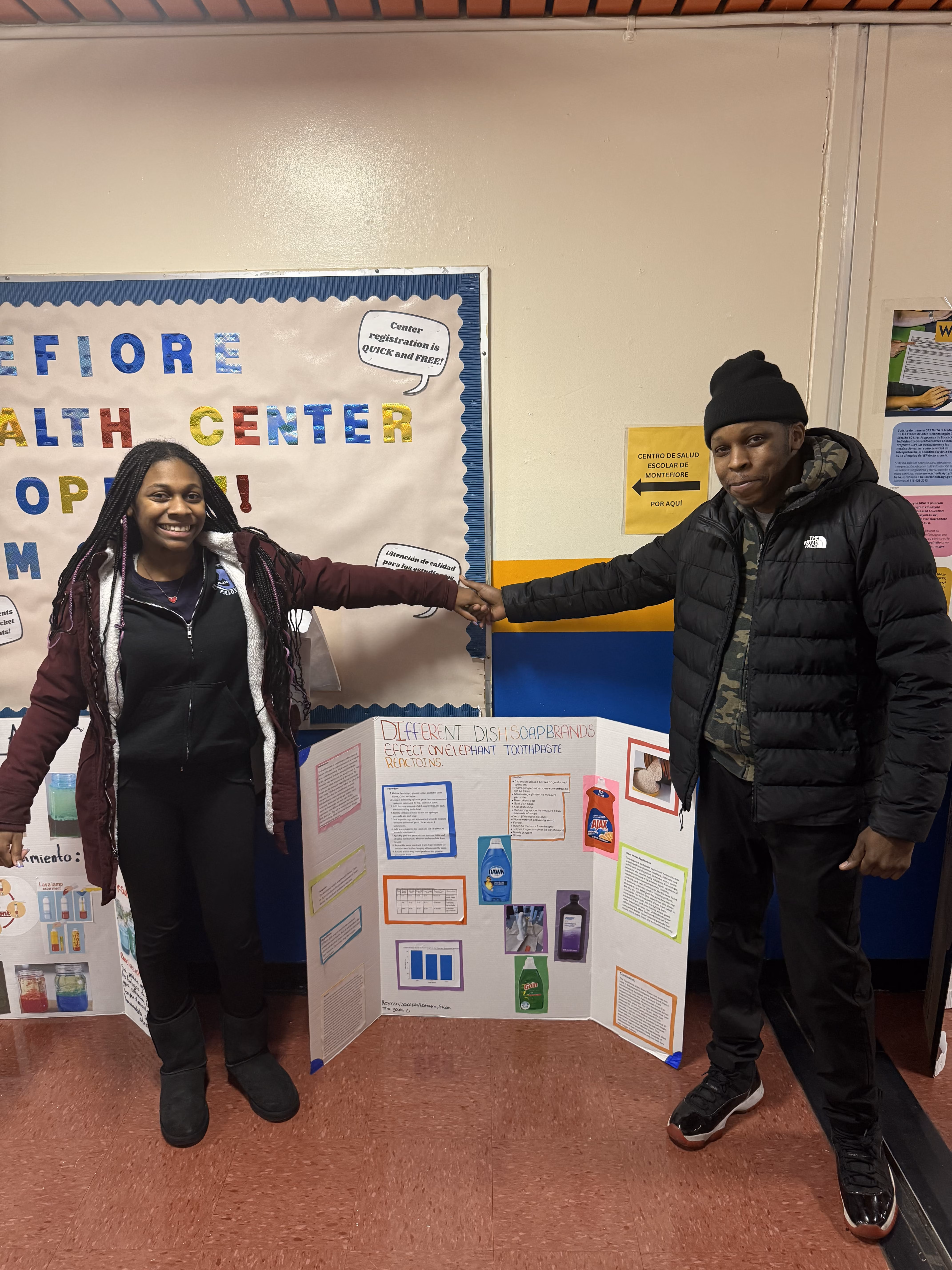Two students presenting dish soap science fair project board