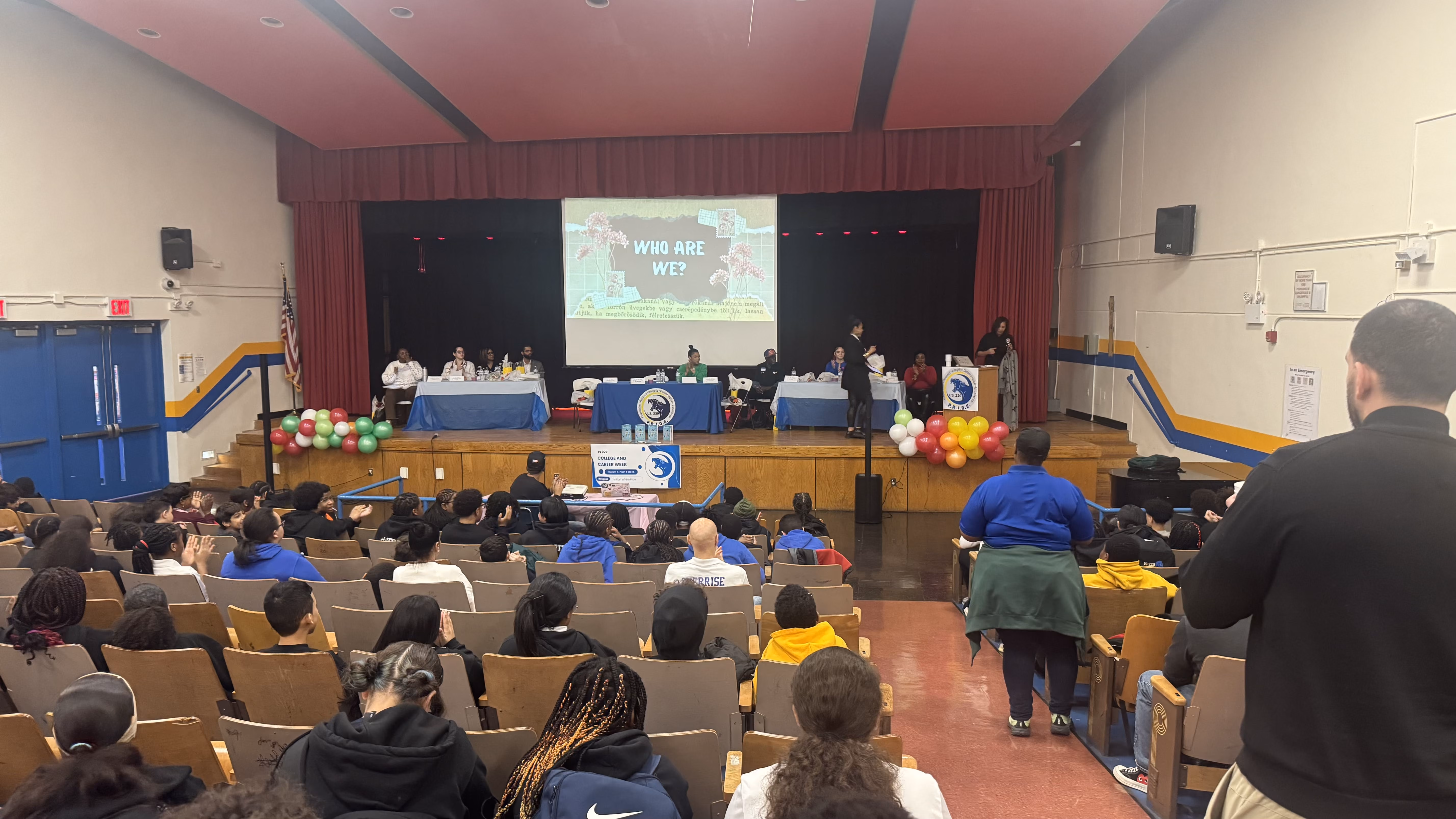Students attending a school assembly with Who Are We presentation on stage