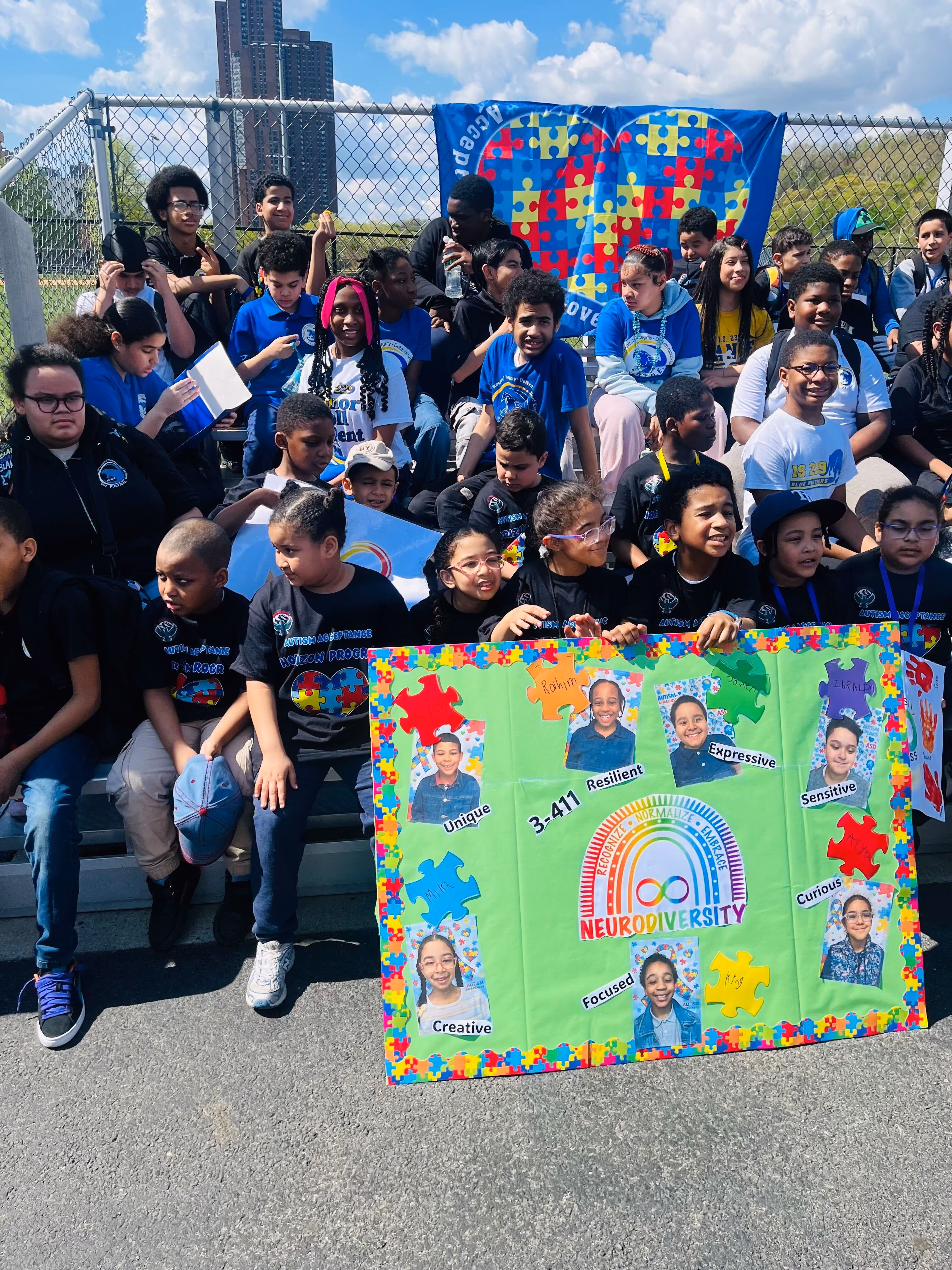 Students holding neurodiversity poster at outdoor autism acceptance event
