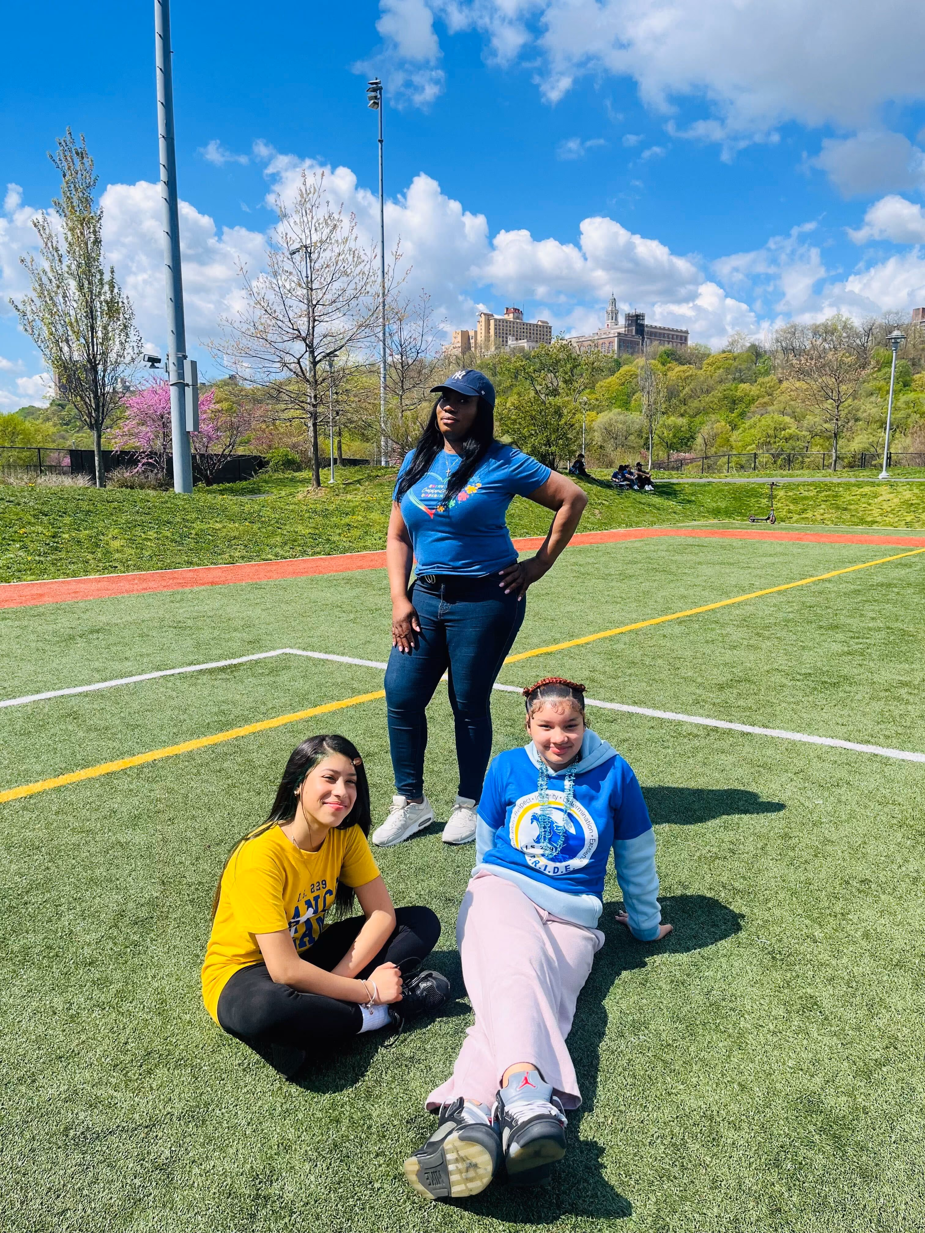Students and staff relaxing on outdoor athletic field on sunny day