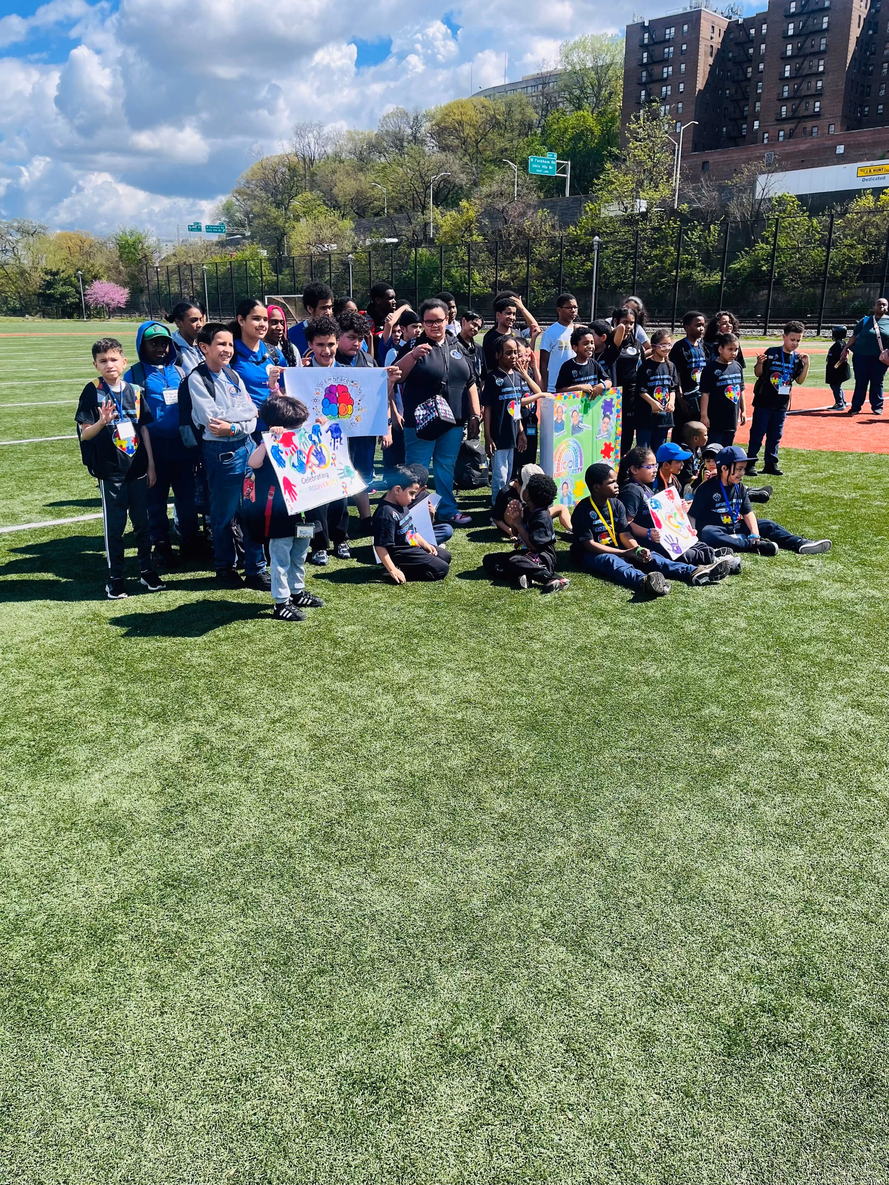 Students holding colorful artwork signs on an outdoor athletic field