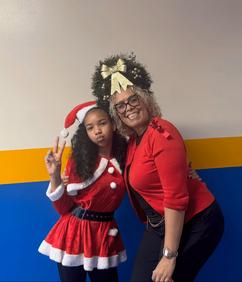 Student and staff member posing in festive holiday outfits at school