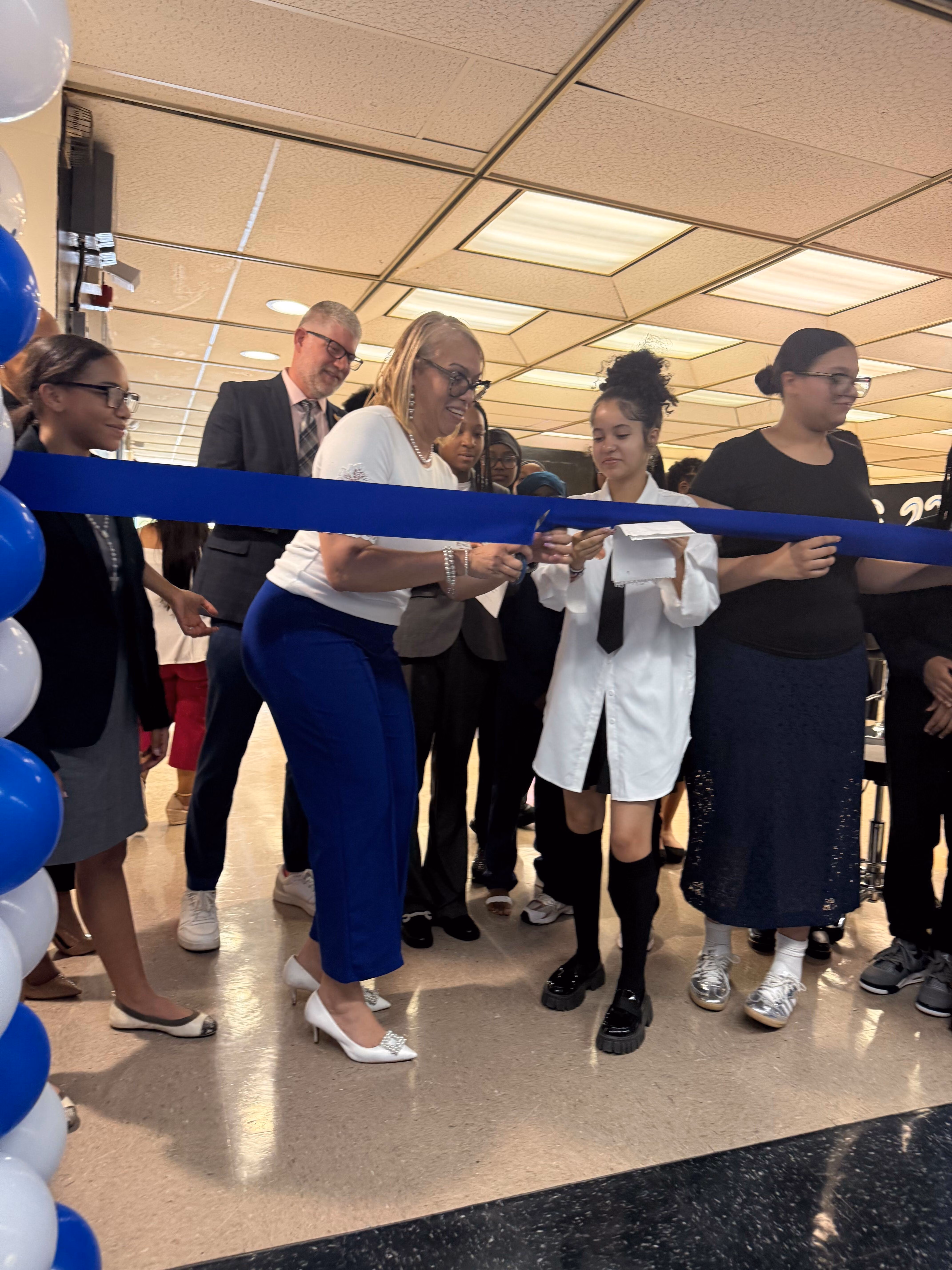 Principal and student cutting blue ribbon at school opening ceremony