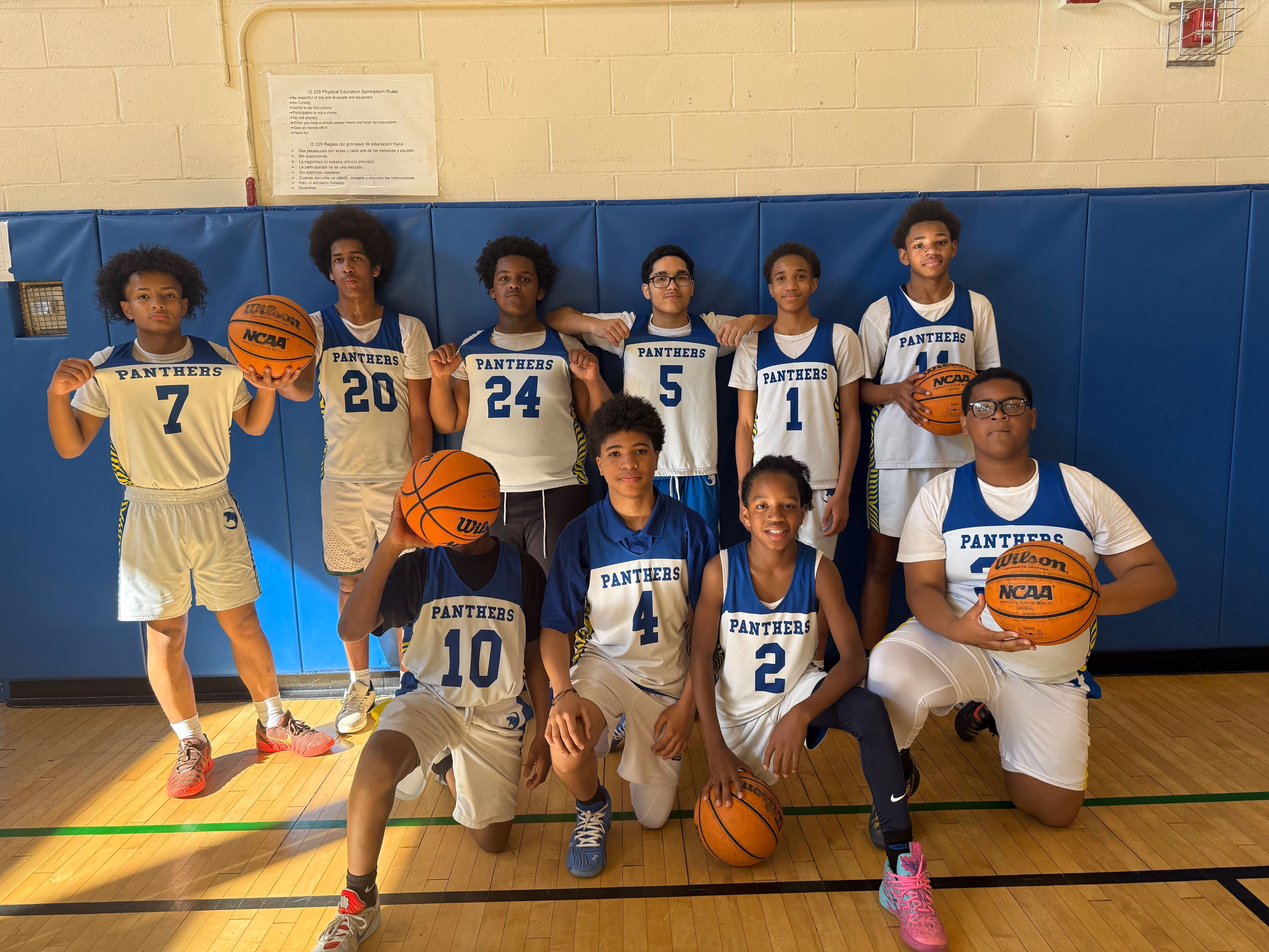 Panthers middle school basketball team poses with basketballs in gym