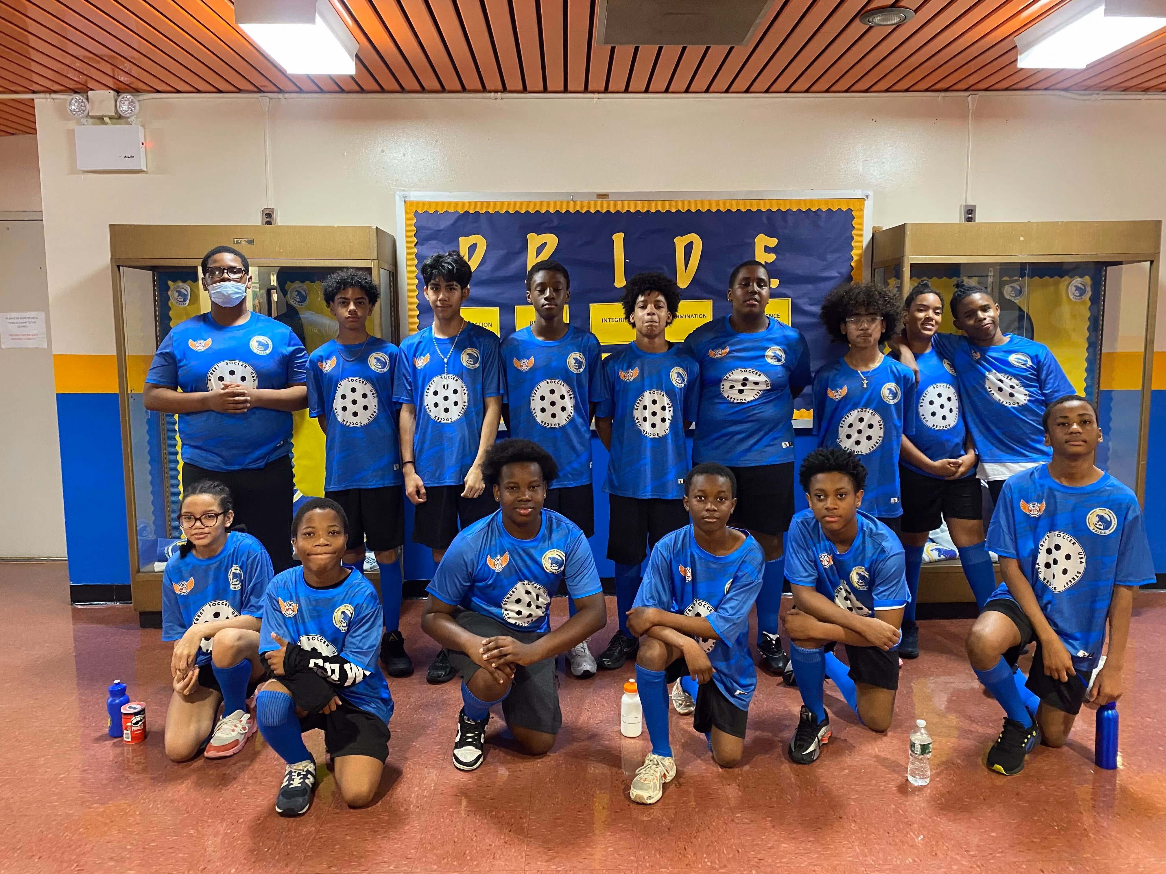 Middle school soccer team posing in blue uniforms indoors