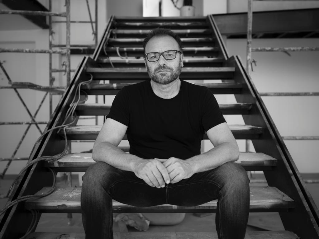 Arquitect Roberto Carlo with glasses and beard sitting on stairs in a construction setting.