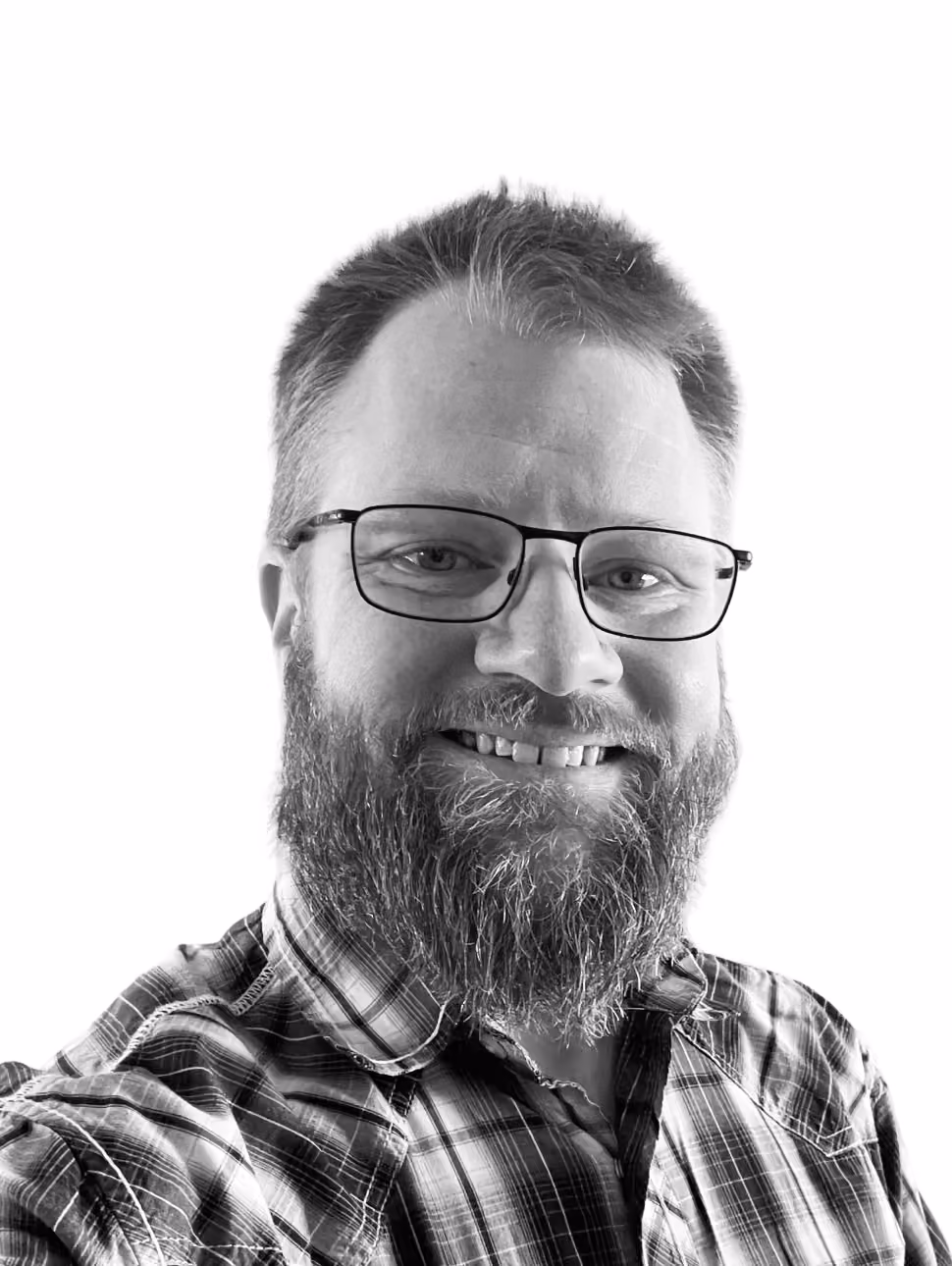Smiling middle-aged man with short hair and a goatee wearing a checked shirt.