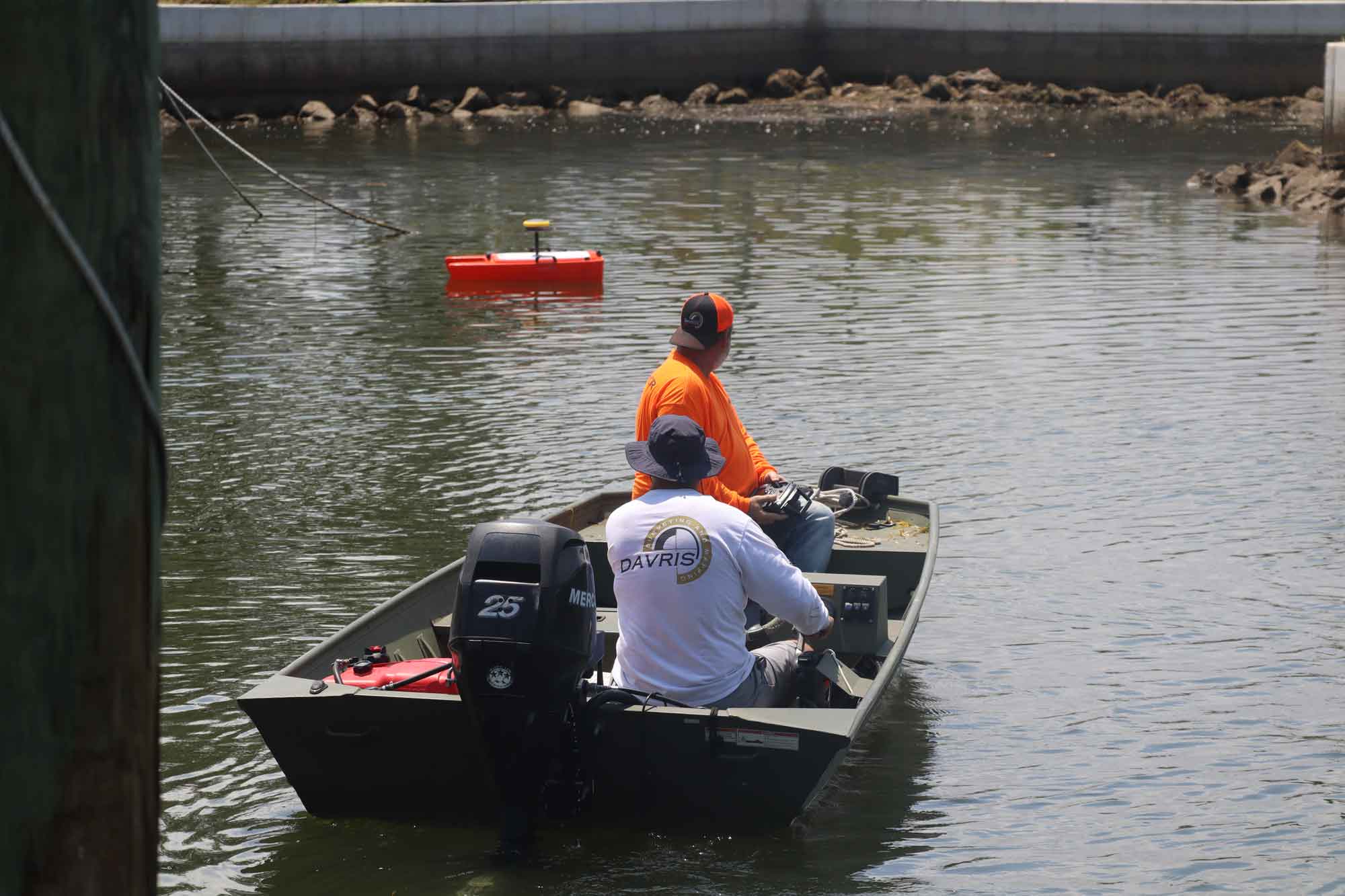 Marine survey crew operating a work boat in a coastal waterway with monitoring equipment for marine and shoreline services.