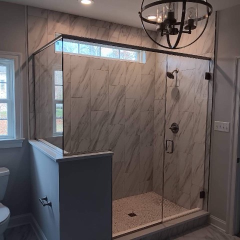 Custom tiled shower with a sliding glass barn door and built-in bench.
