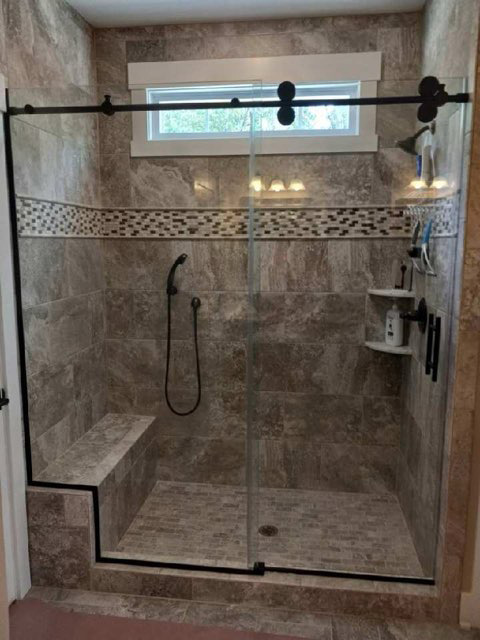 Marble-tiled walk-in shower with a frameless glass enclosure and built-in niche.
