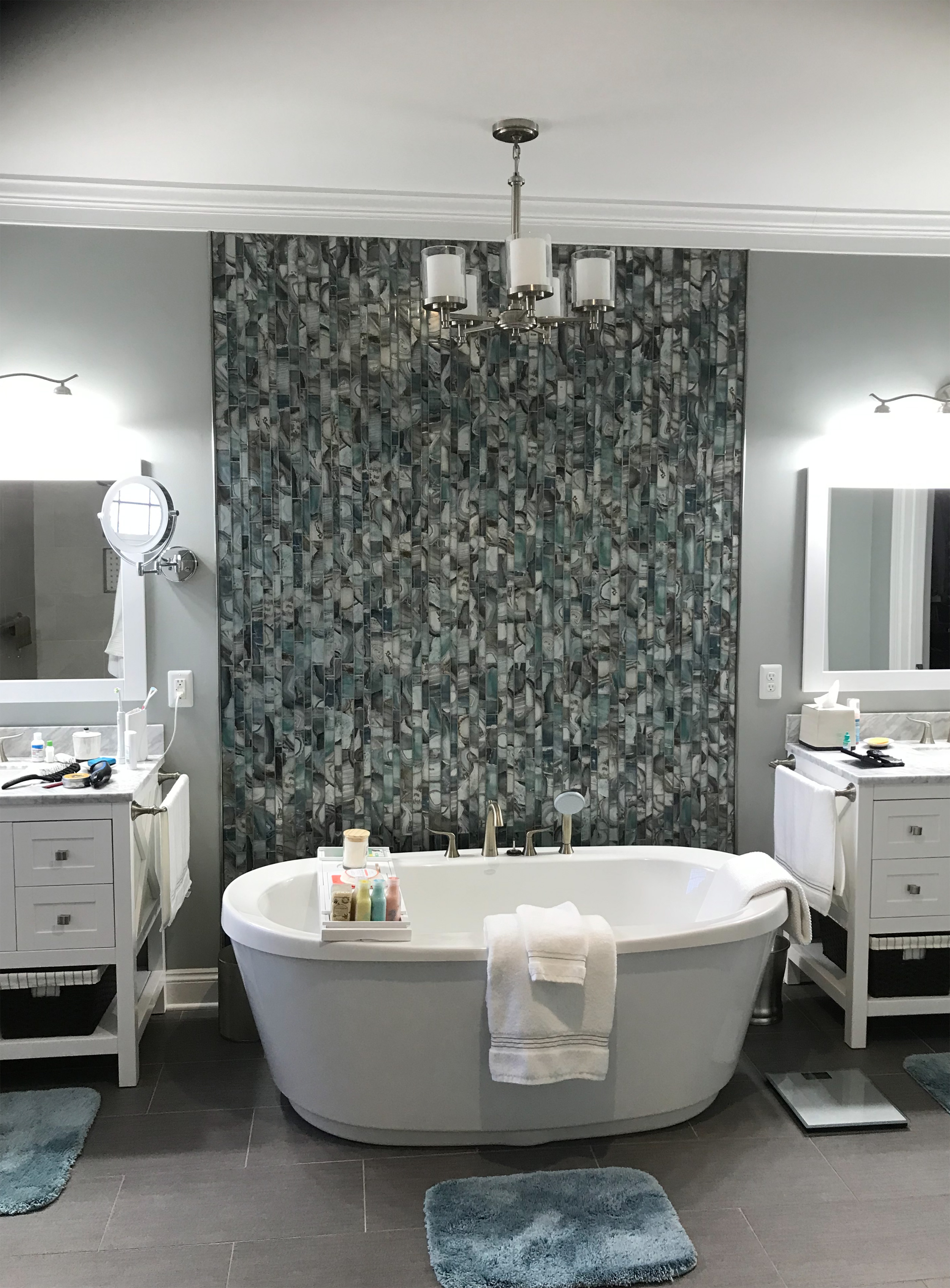 Modern bathroom with a freestanding tub, patterned accent wall, and double vanity.