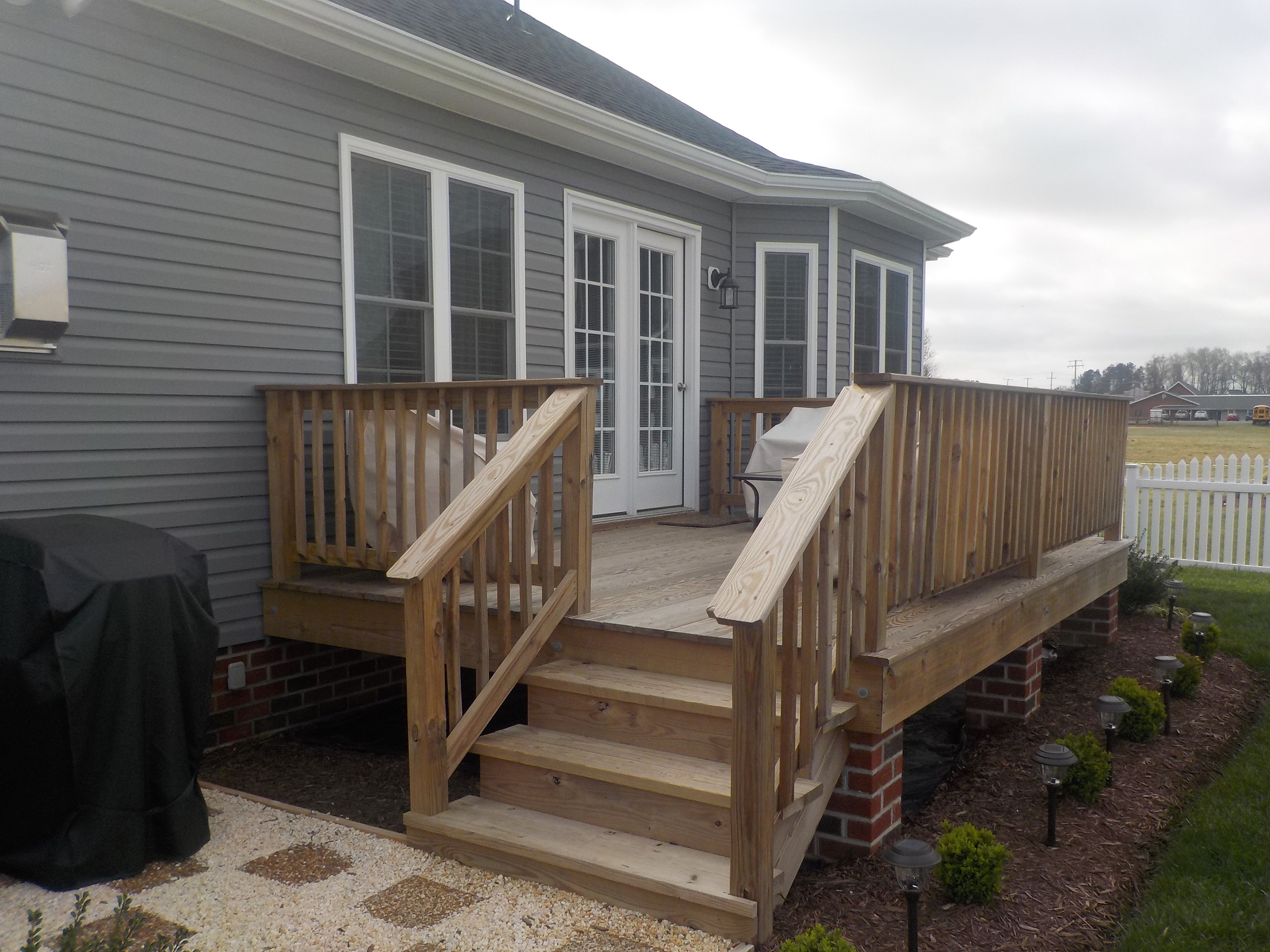 Ground-level wood deck with wide stairs and matching railings.