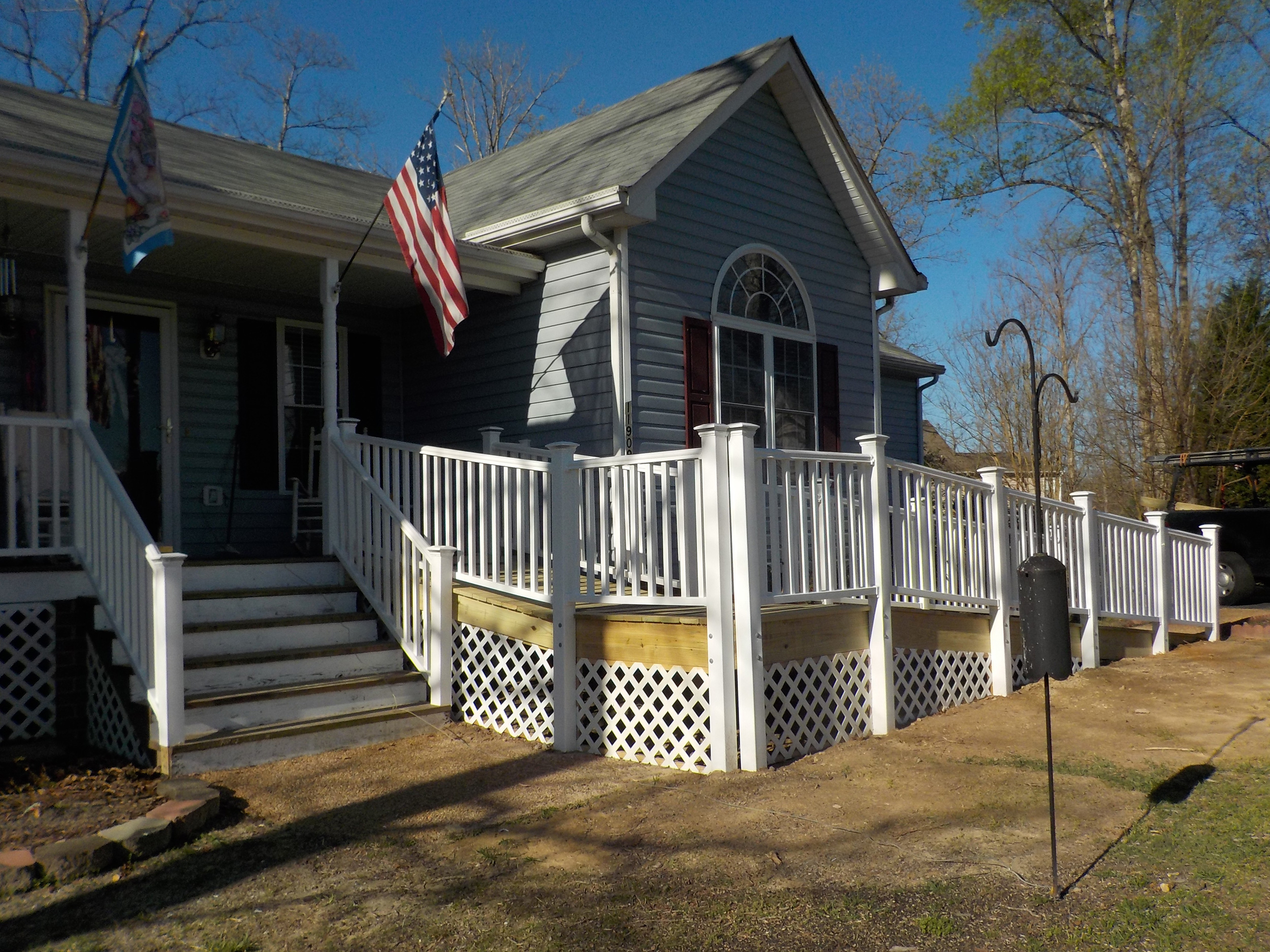 Elevated backyard deck with white railings, stairs, and lattice skirting.