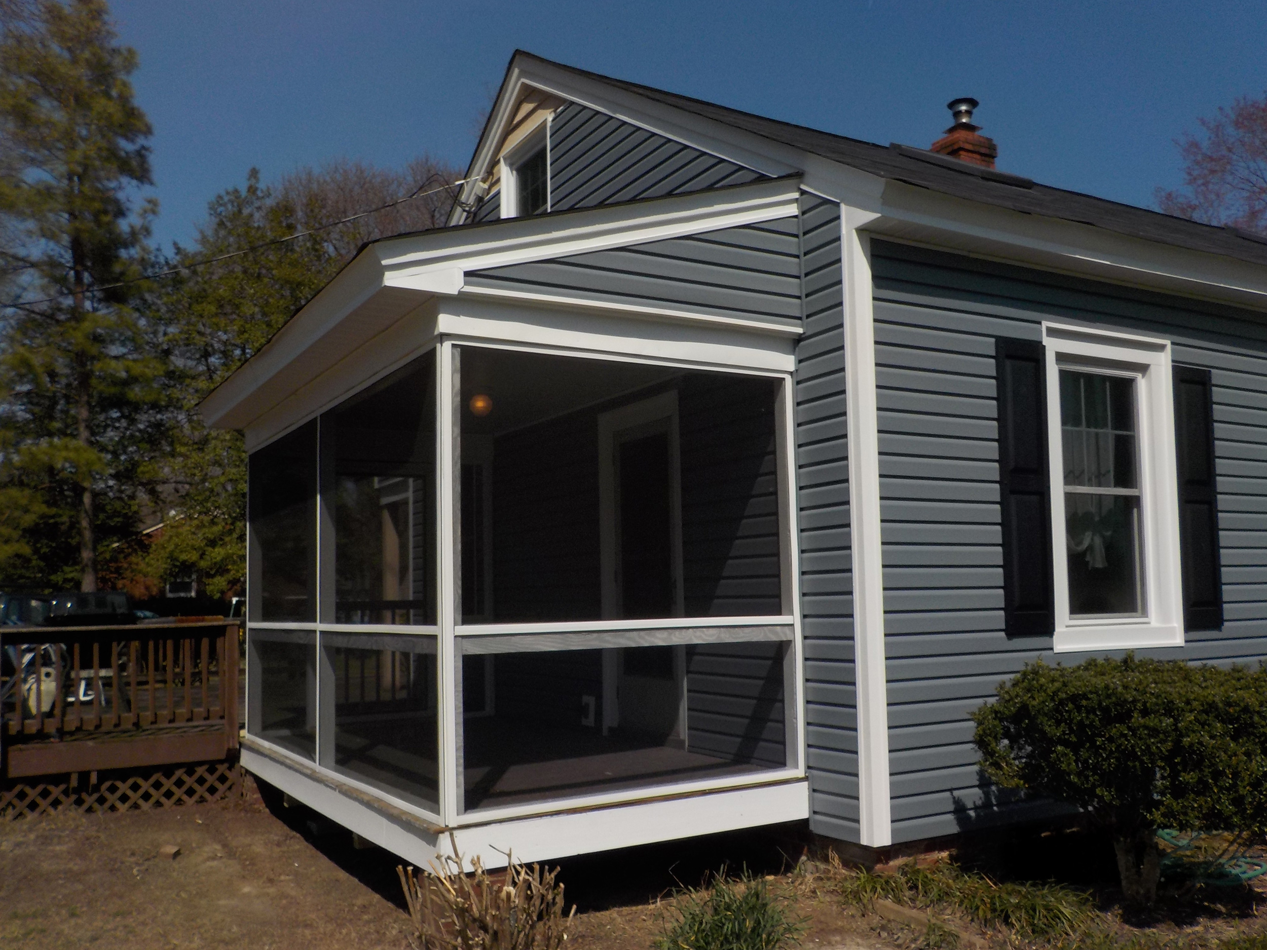 Screened porch addition with white framing attached to a gray-sided home.