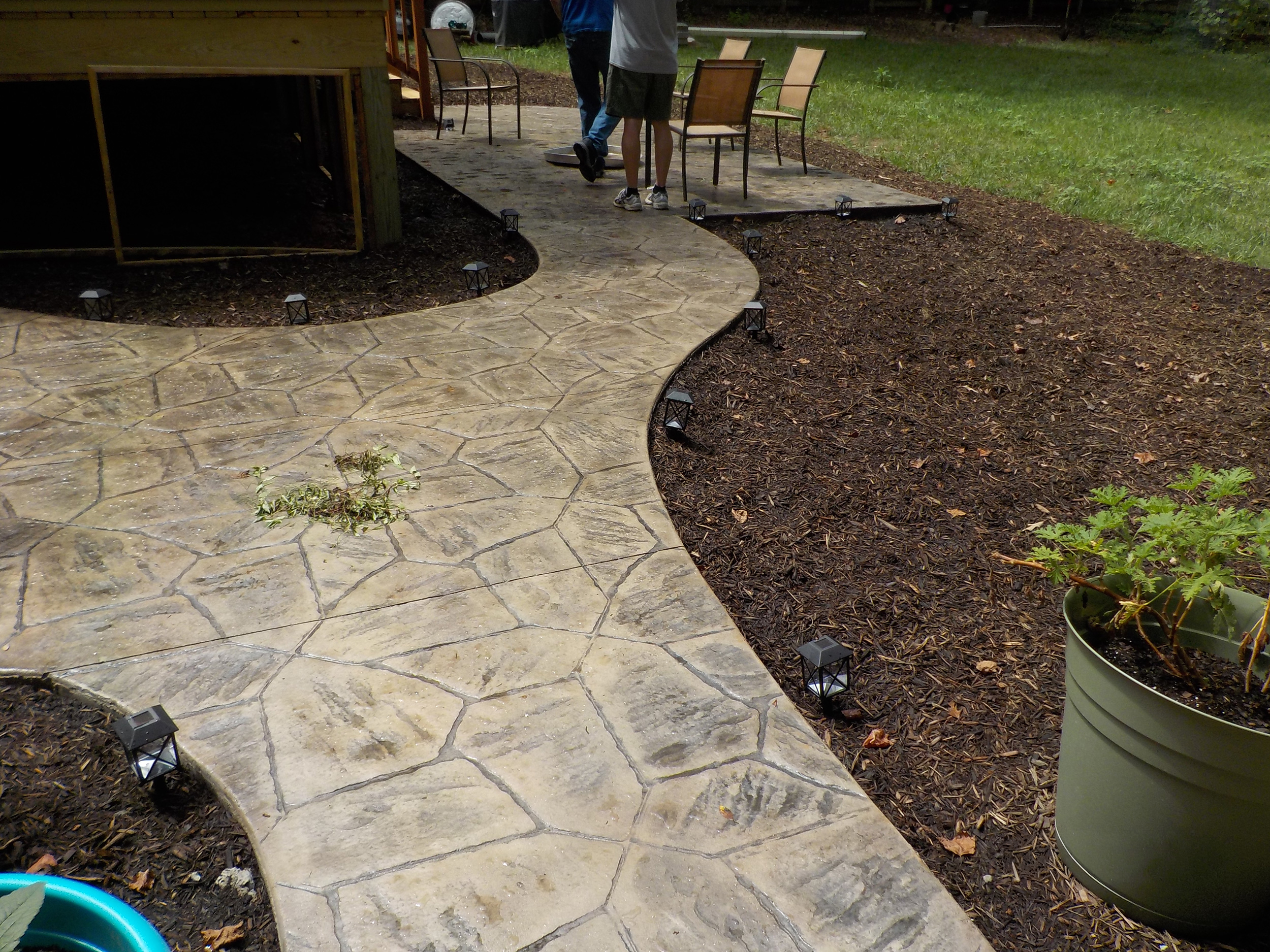 Curved stamped concrete walkway bordered by landscaped garden beds.
