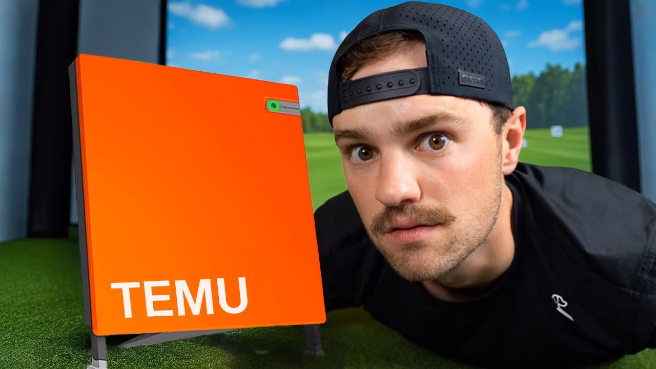 Man in a black cap inspecting a bright orange board labeled TEMU on artificial grass.