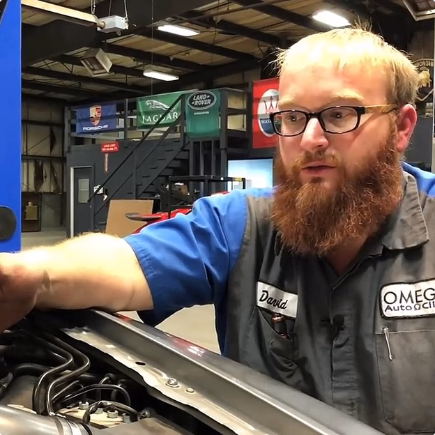Smiling middle-aged man wearing a dark coat in a warmly lit indoor setting.