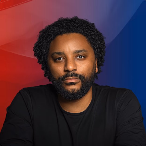 Smiling middle-aged man wearing a dark coat in a warmly lit indoor setting.
