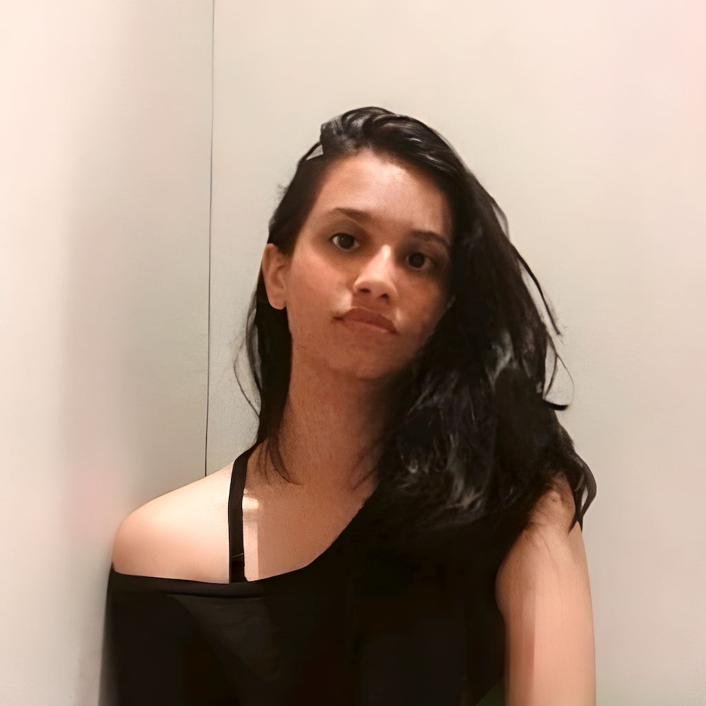 Portrait of a woman with long black hair wearing a black off-shoulder top against a plain light background.