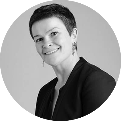 Black and white headshot of a smiling woman with short dark hair wearing a dark blazer and dangling earrings against a plain background.
