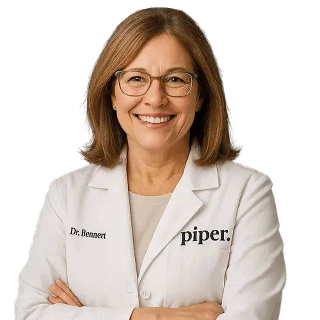 Smiling female doctor with shoulder-length brown hair and glasses wearing a white lab coat with 'Dr. Bennert' and 'piper.' text.