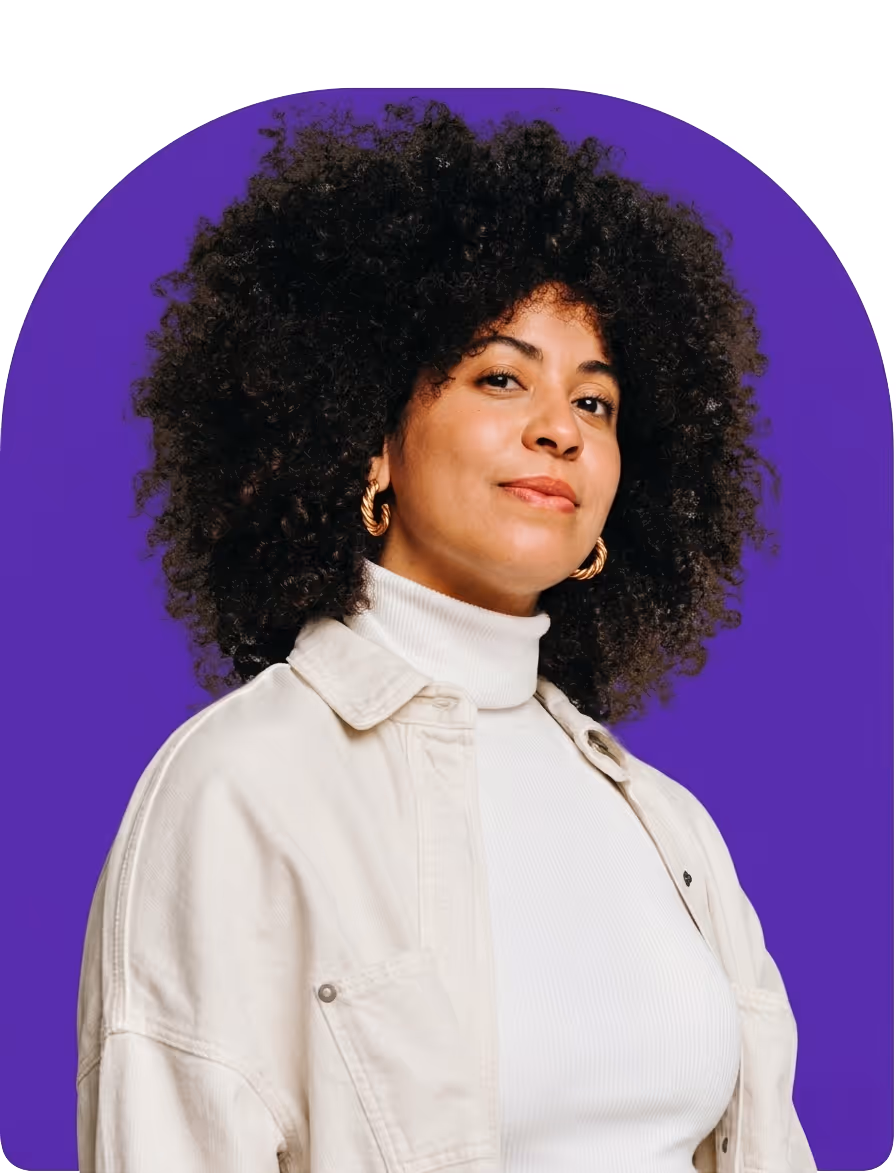 Confident woman with curly hair wearing a white turtleneck and beige jacket against a purple background.