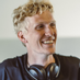 Photo of an entrepreneur smiling, wearing headphones around his neck.