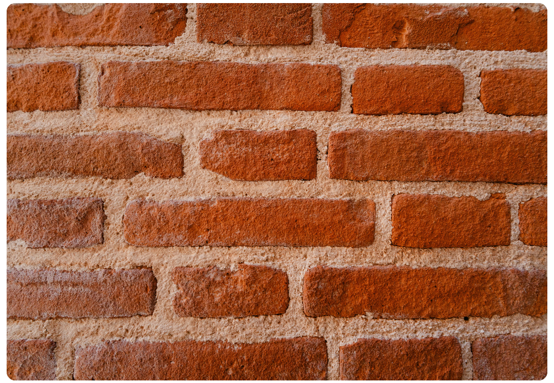 Close-up of a red brick wall with rough texture and light mortar lines.