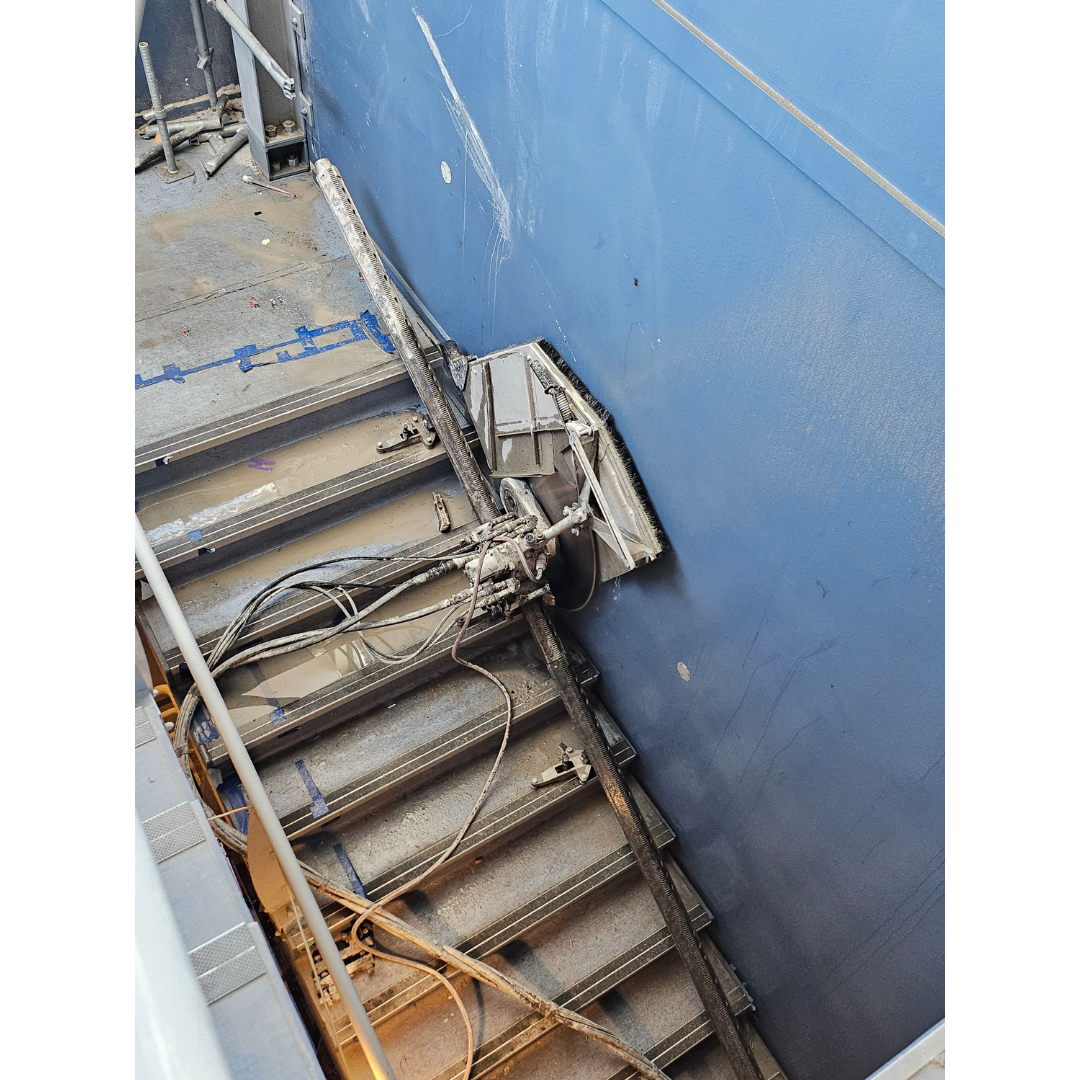 Industrial saw machine cutting into a blue wall on a stairway.