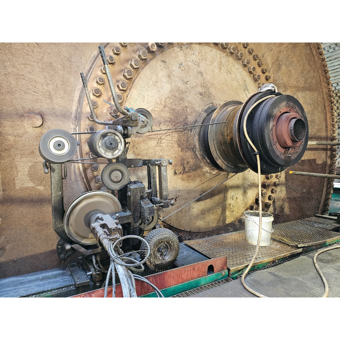 Close-up of an industrial machine with multiple rotating pulleys connected by belts and wires on a metal platform.