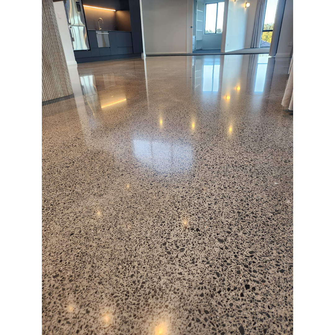 Polished terrazzo floor reflecting kitchen cabinets, windows, and ceiling lights in a modern interior.