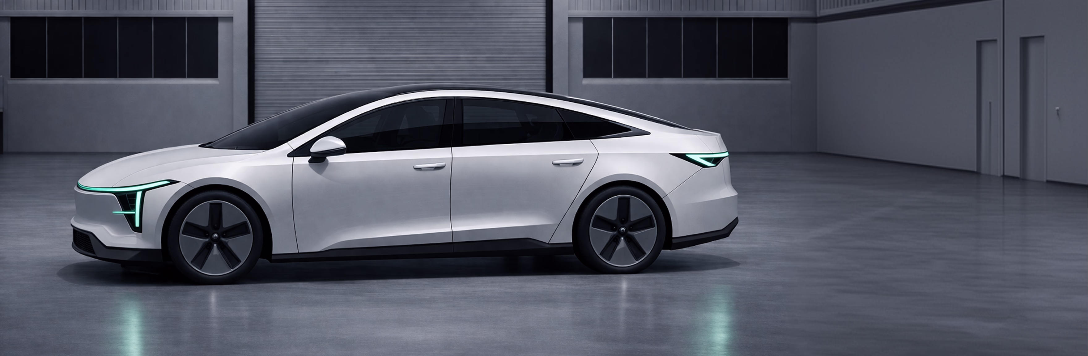 Silver compact electric van with front door and sliding side door open, showing interior seats and storage area, parked inside a large industrial garage.
