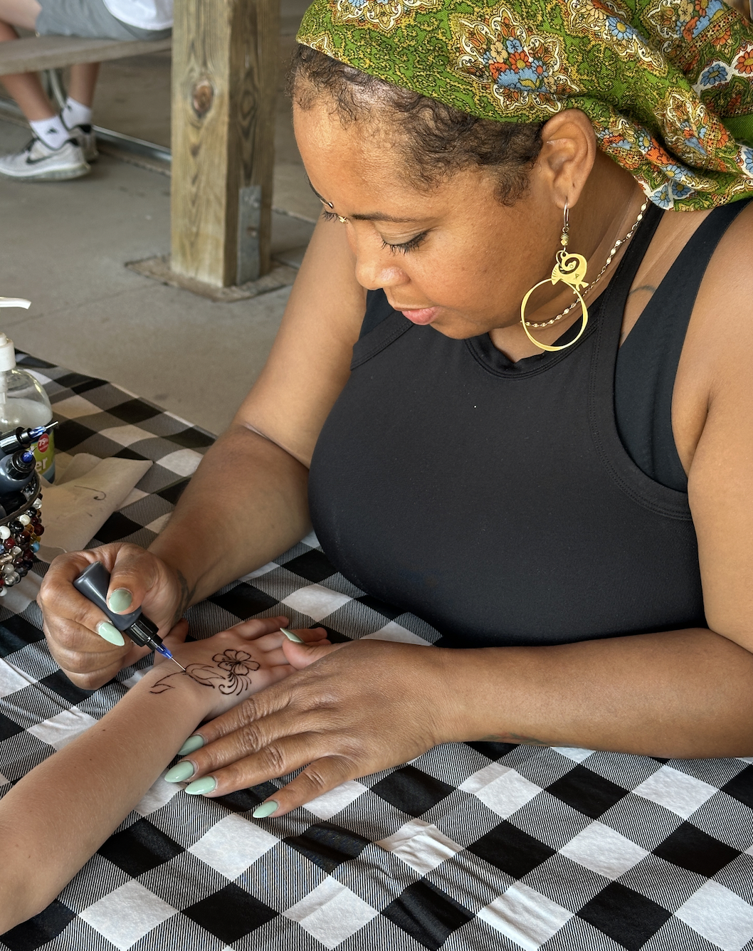 Henna artist creating intricate body art for a guest
