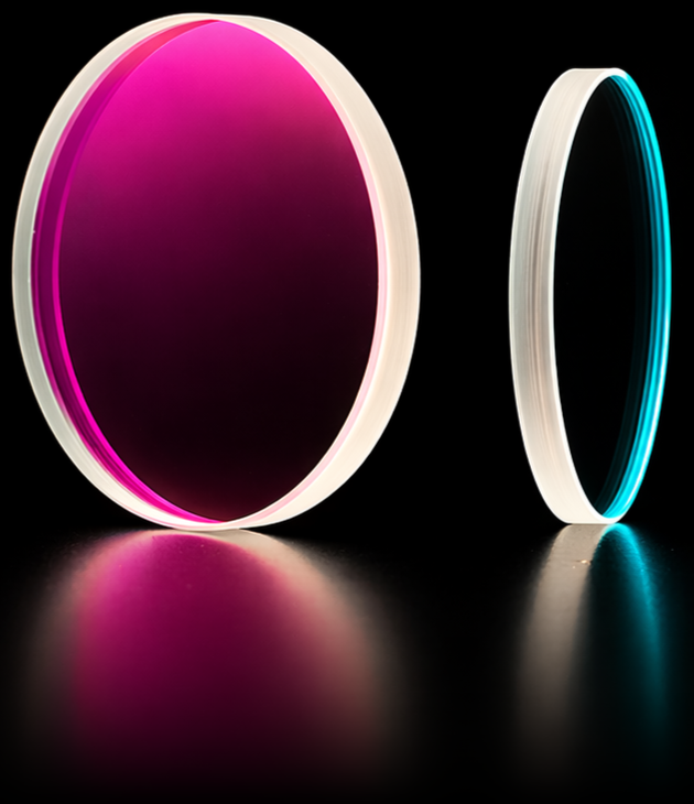 Two circular multi-band optical filters side by side — one large filter with a deep magenta and pink interference coating, and one smaller uncoated clear substrate, showing a mounted and unmounted configuration.