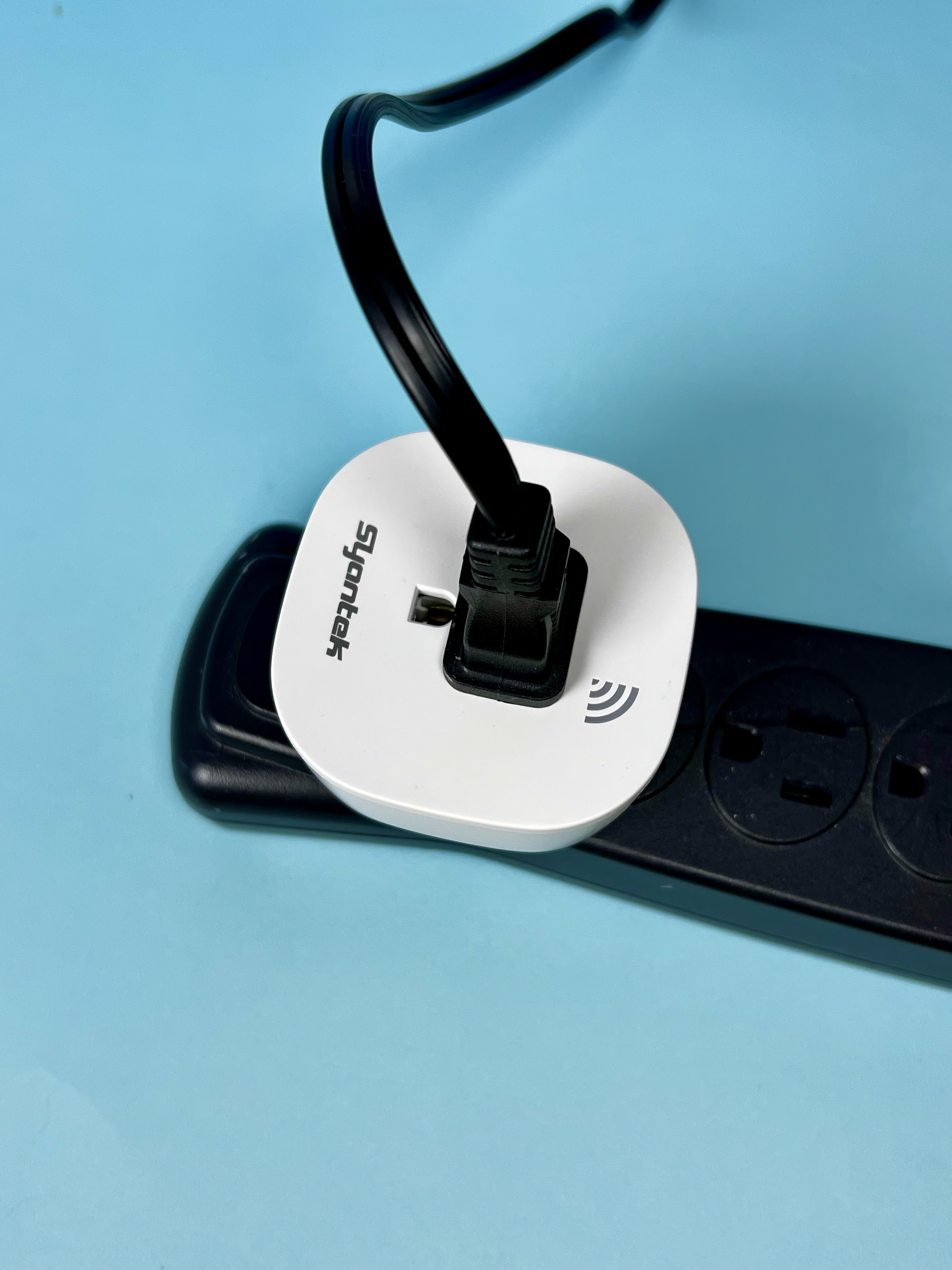 A white remote-control outlet plug connected to a power strip on a blue background.