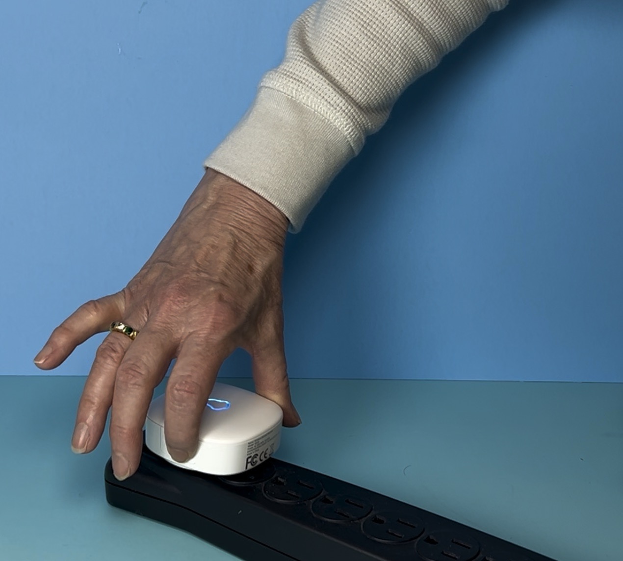 A hand pressing a wireless doorbell receiver to change the volume. 
