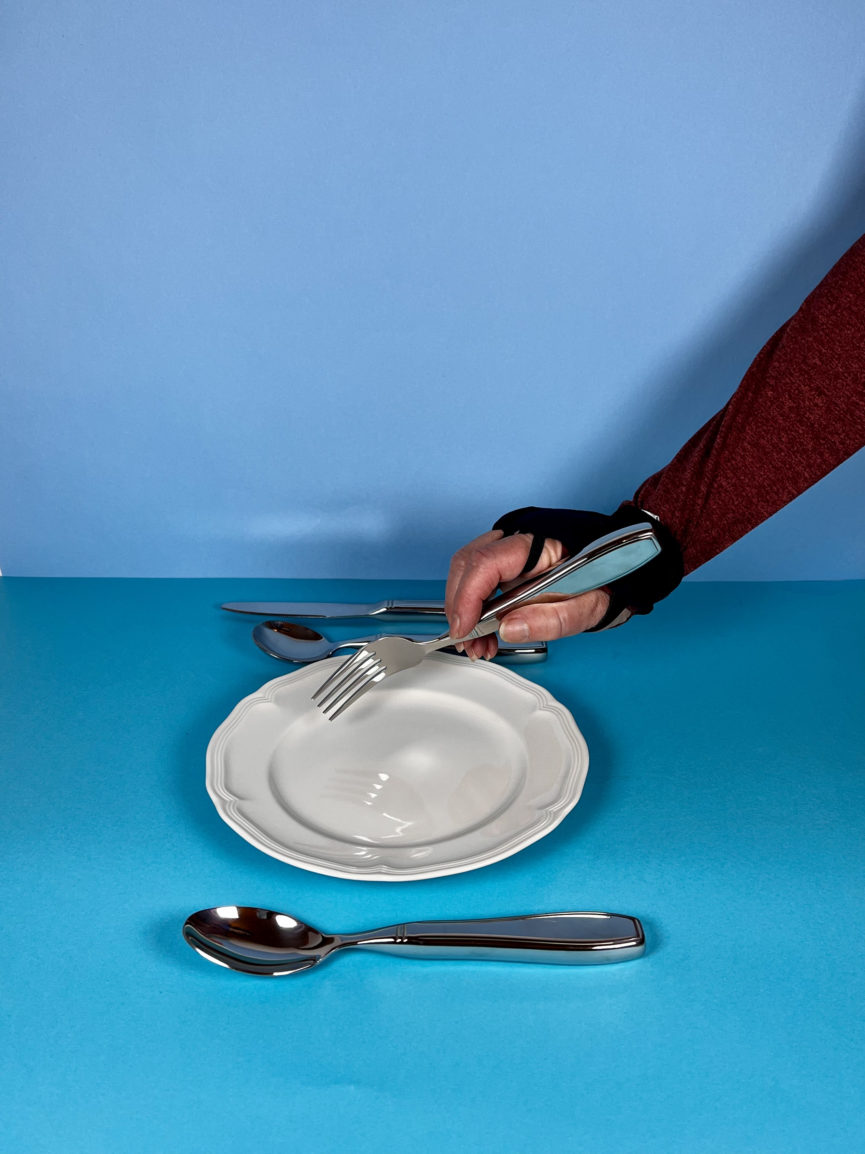 a hand in a weighted glove and weighted silverware for tremor