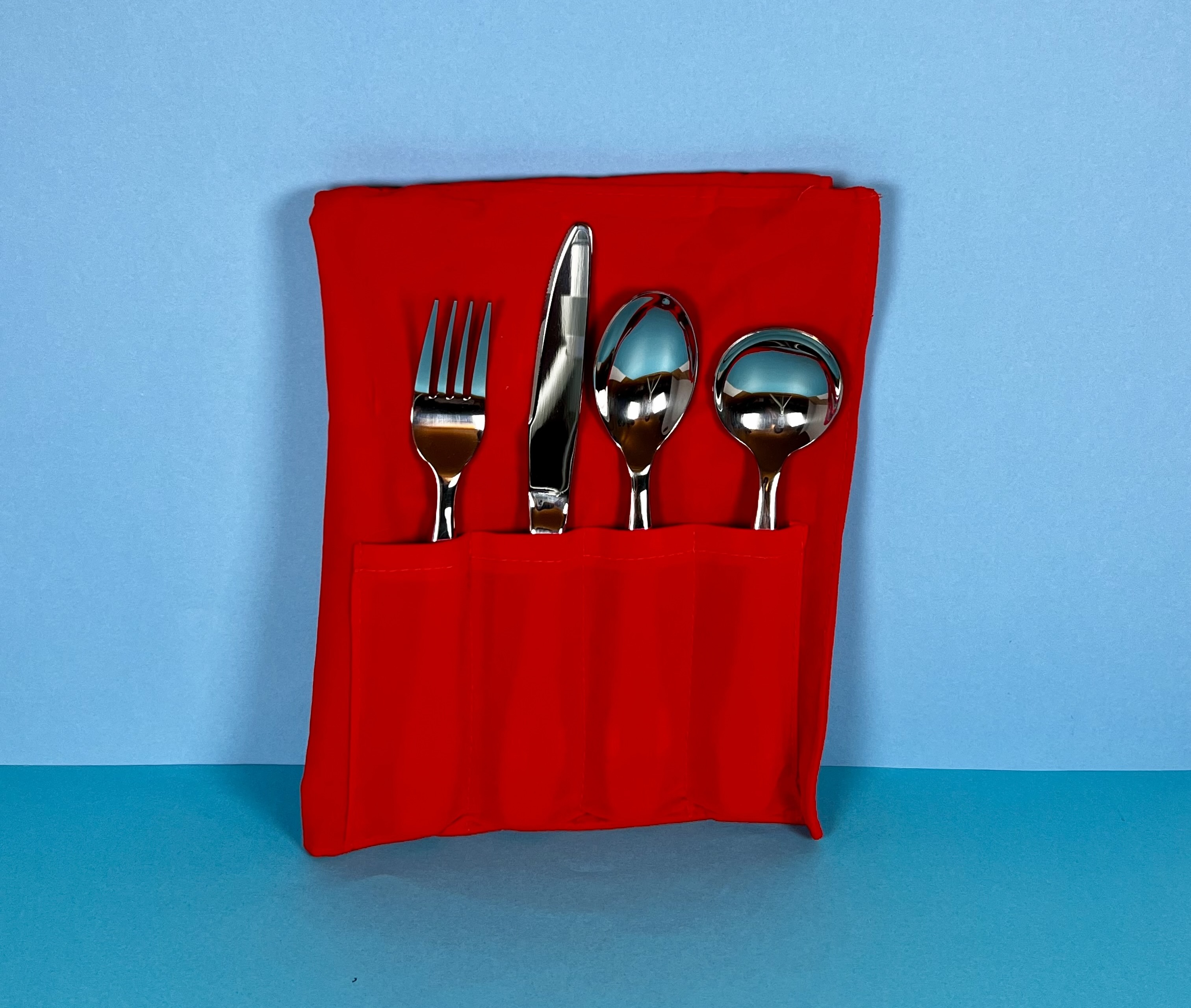 A bright red velvet fabric case with weighted fork, knife, spoon and soup spoon 