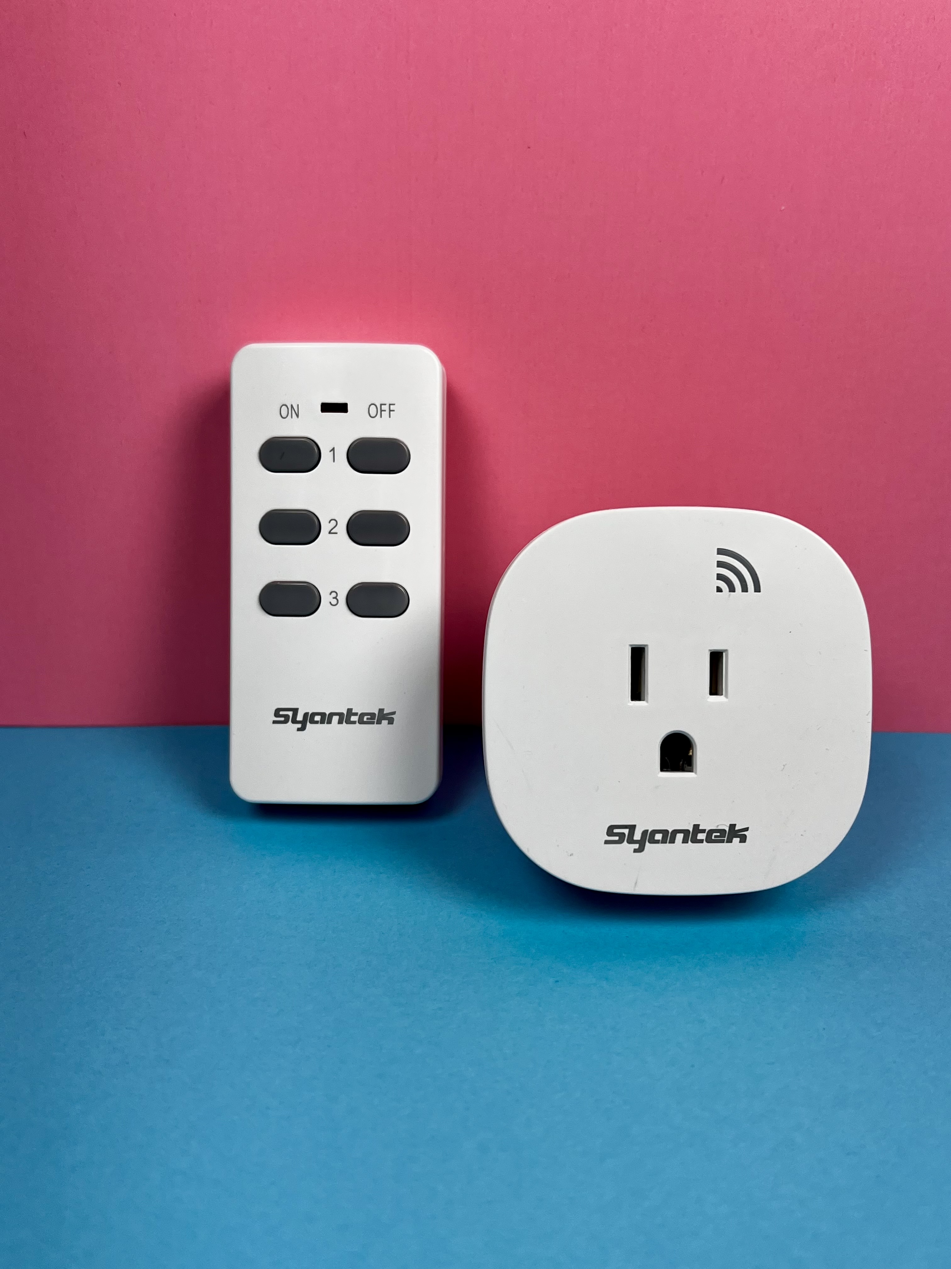 A white remote-control outlet plug displayed next to its handheld remote on a pink and blue background.