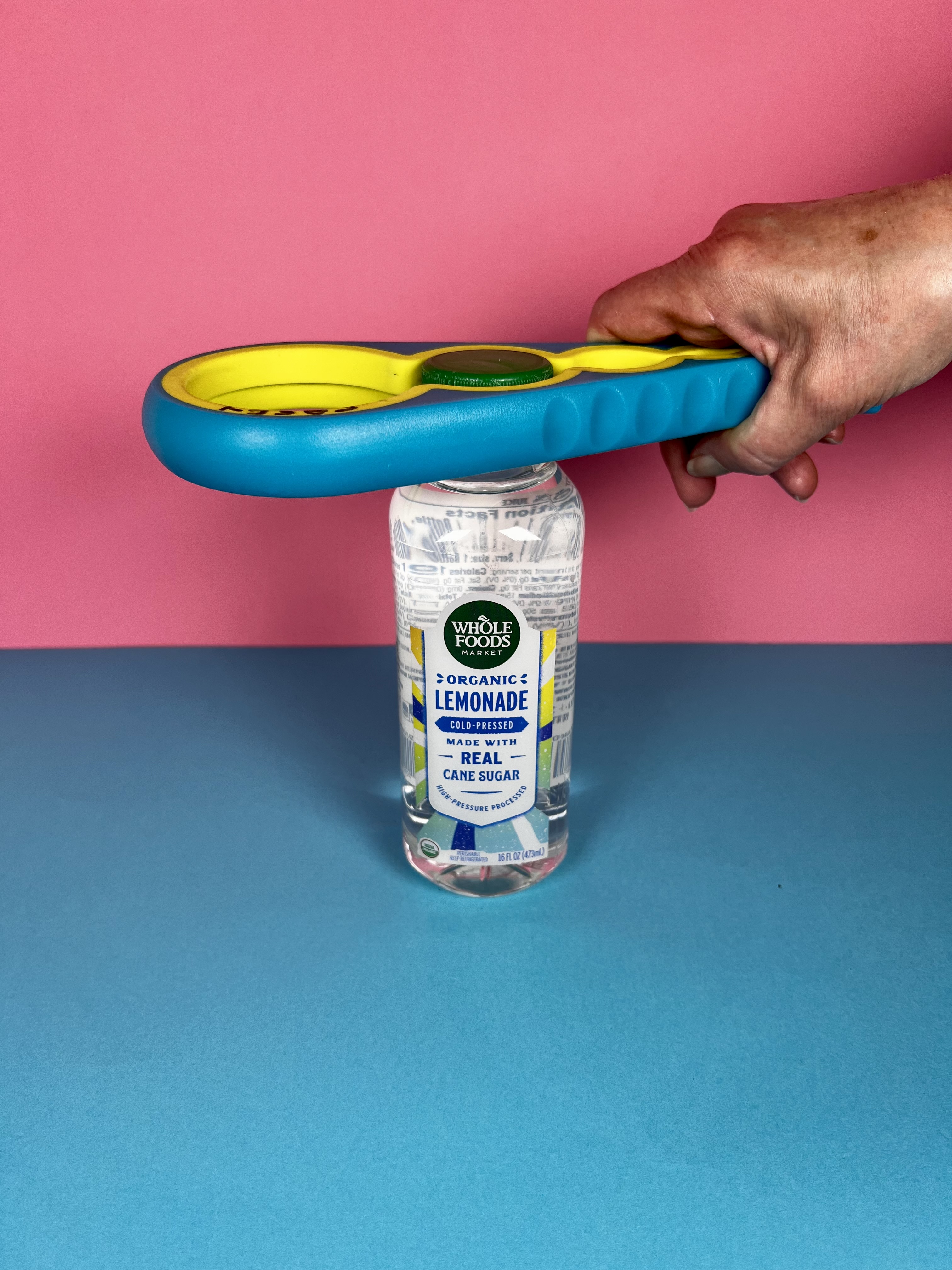 A colorful multi-size opener attached to the cap of a small water bottle.