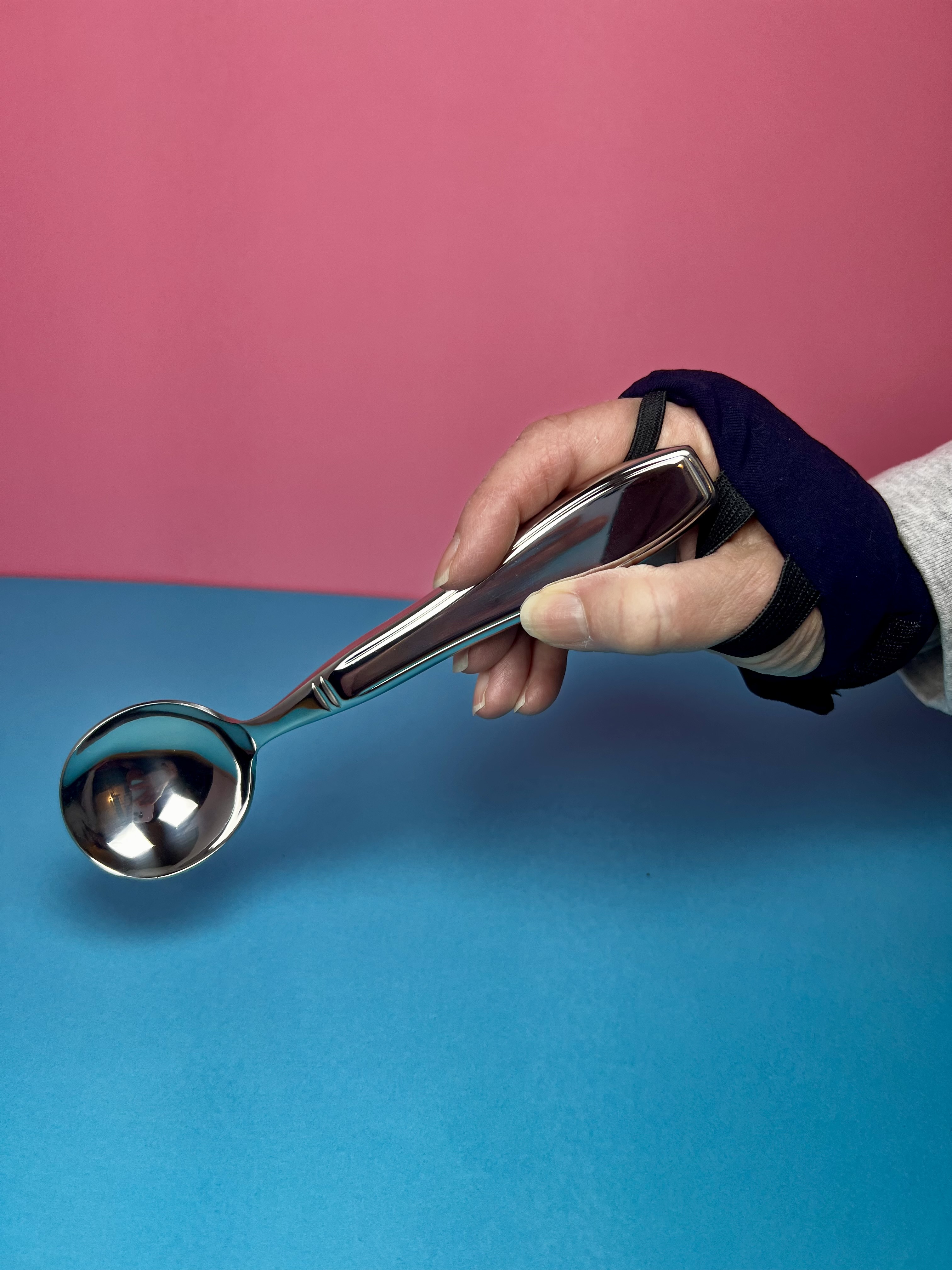 a hand wearing a weighted glove with a weighted spoon