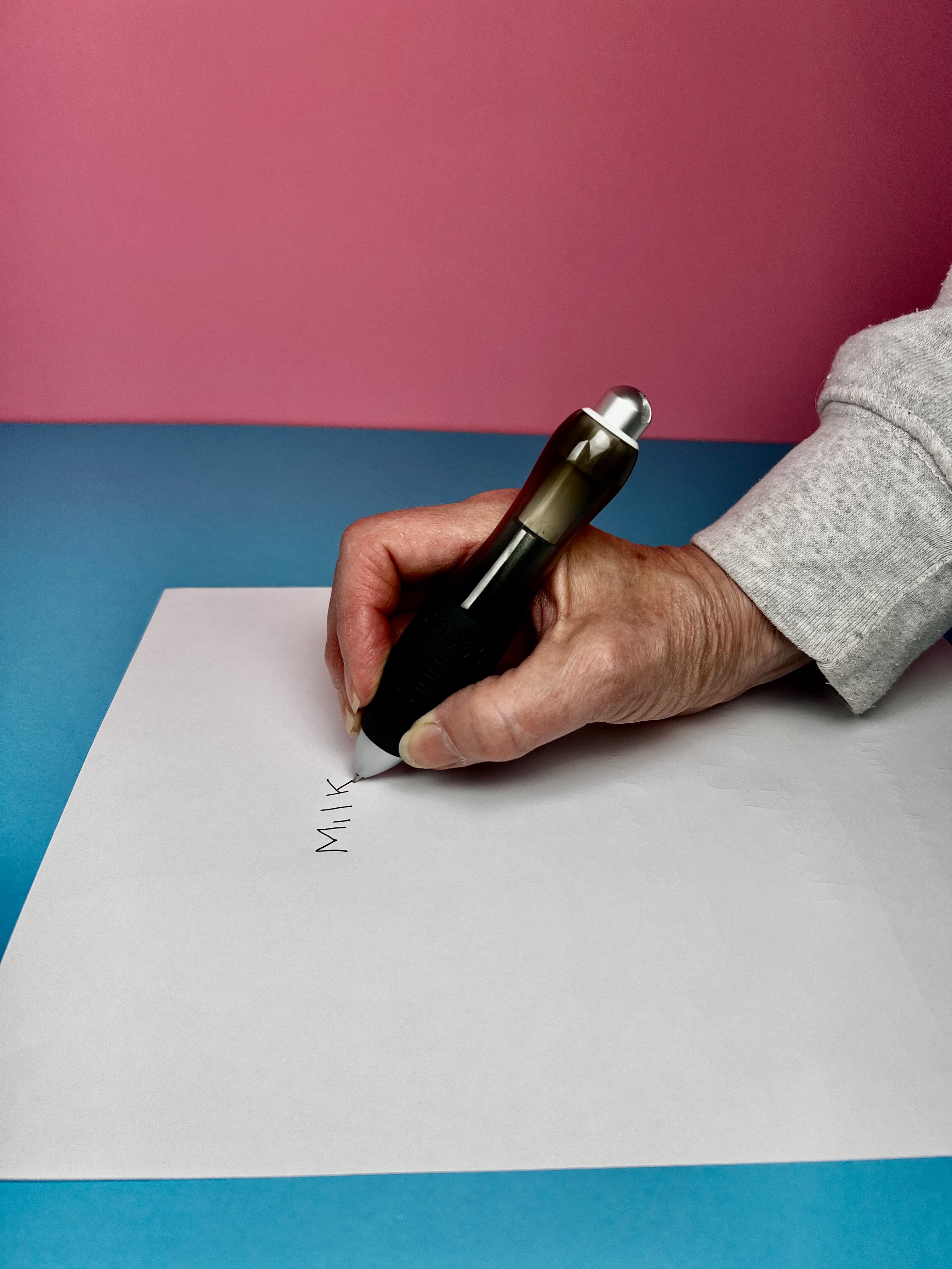 a hand holding a weighted pen for tremor writing