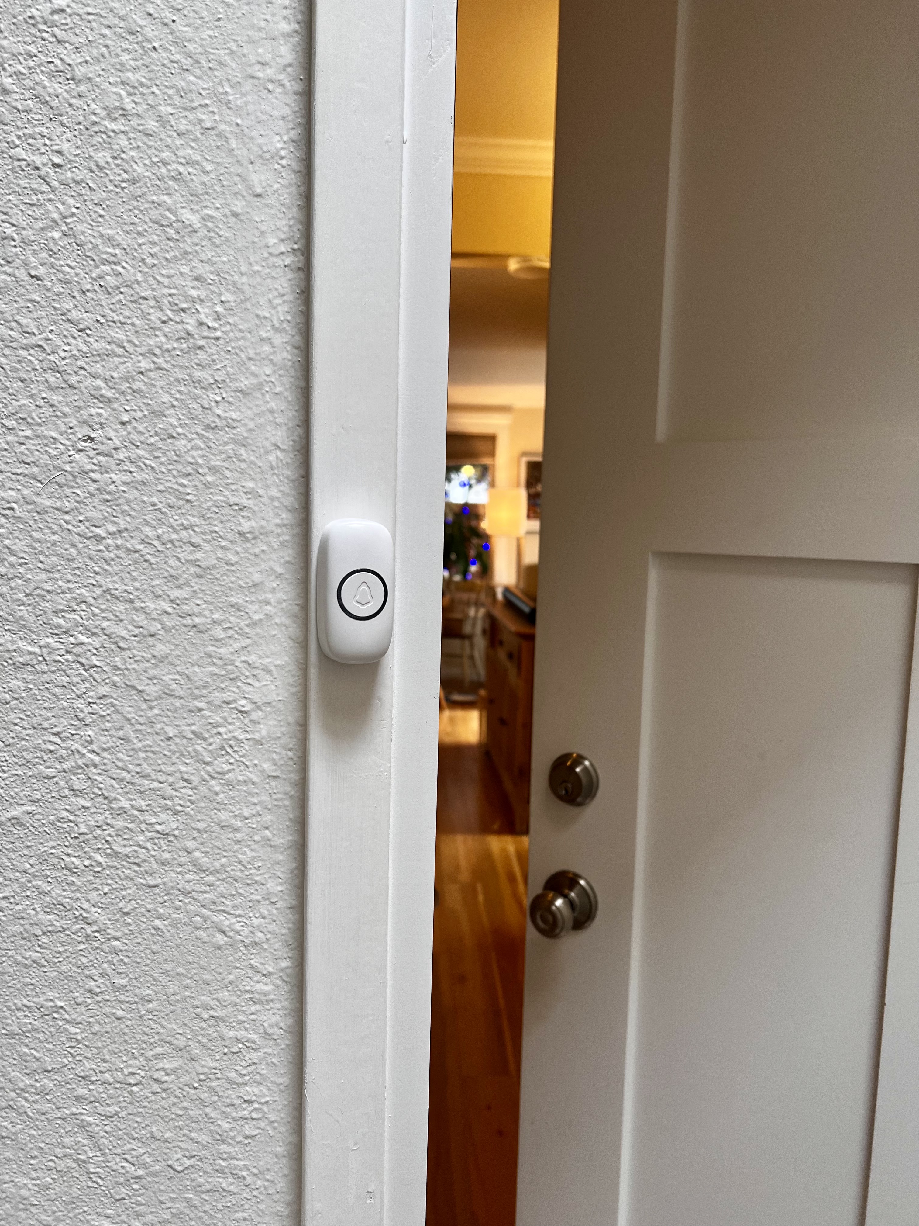 A wireless doorbell button mounted on a wall beside a door.