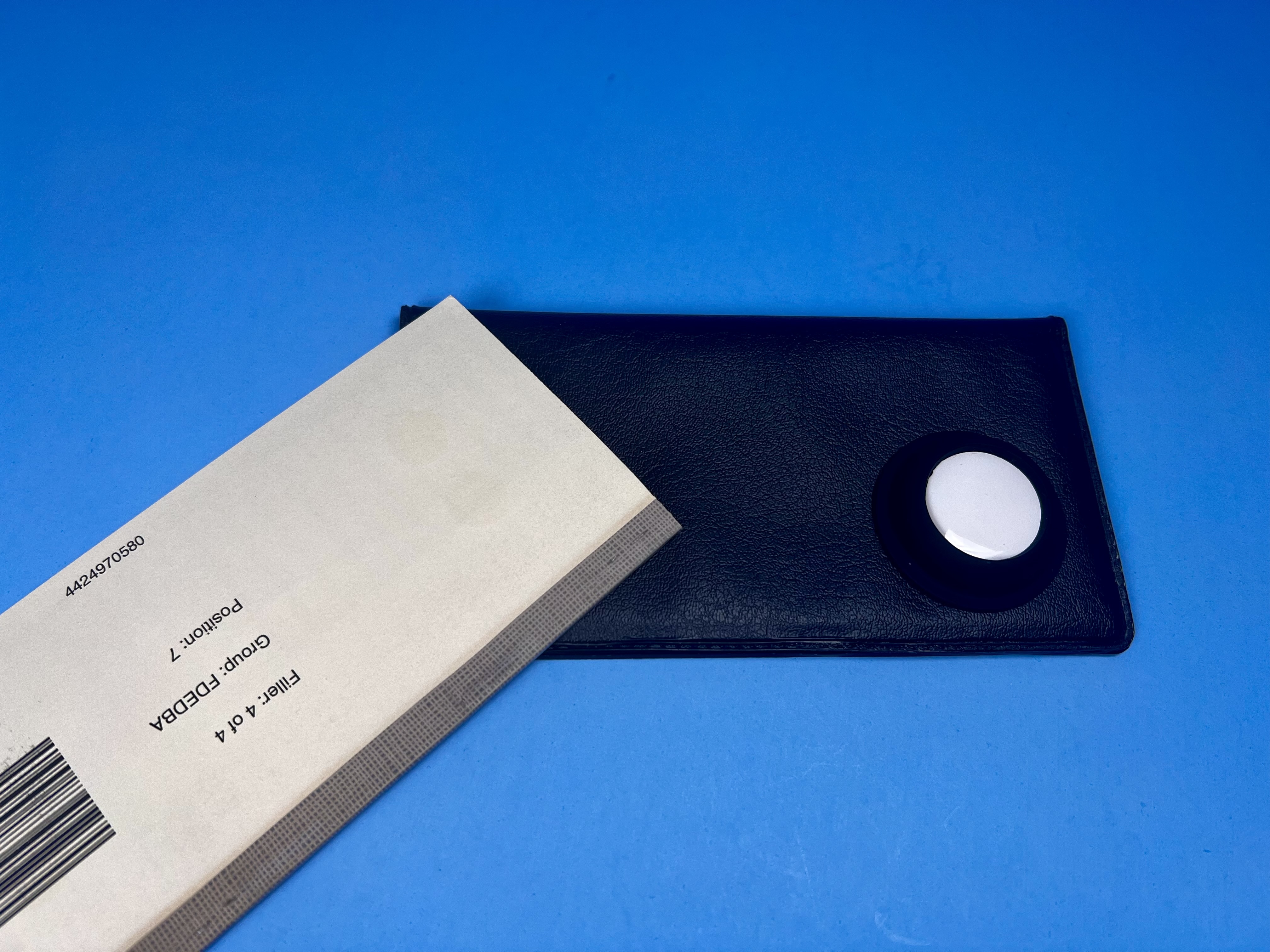 Checkbook on a blue background with a white AirTag attached by a black silicone holder to it.