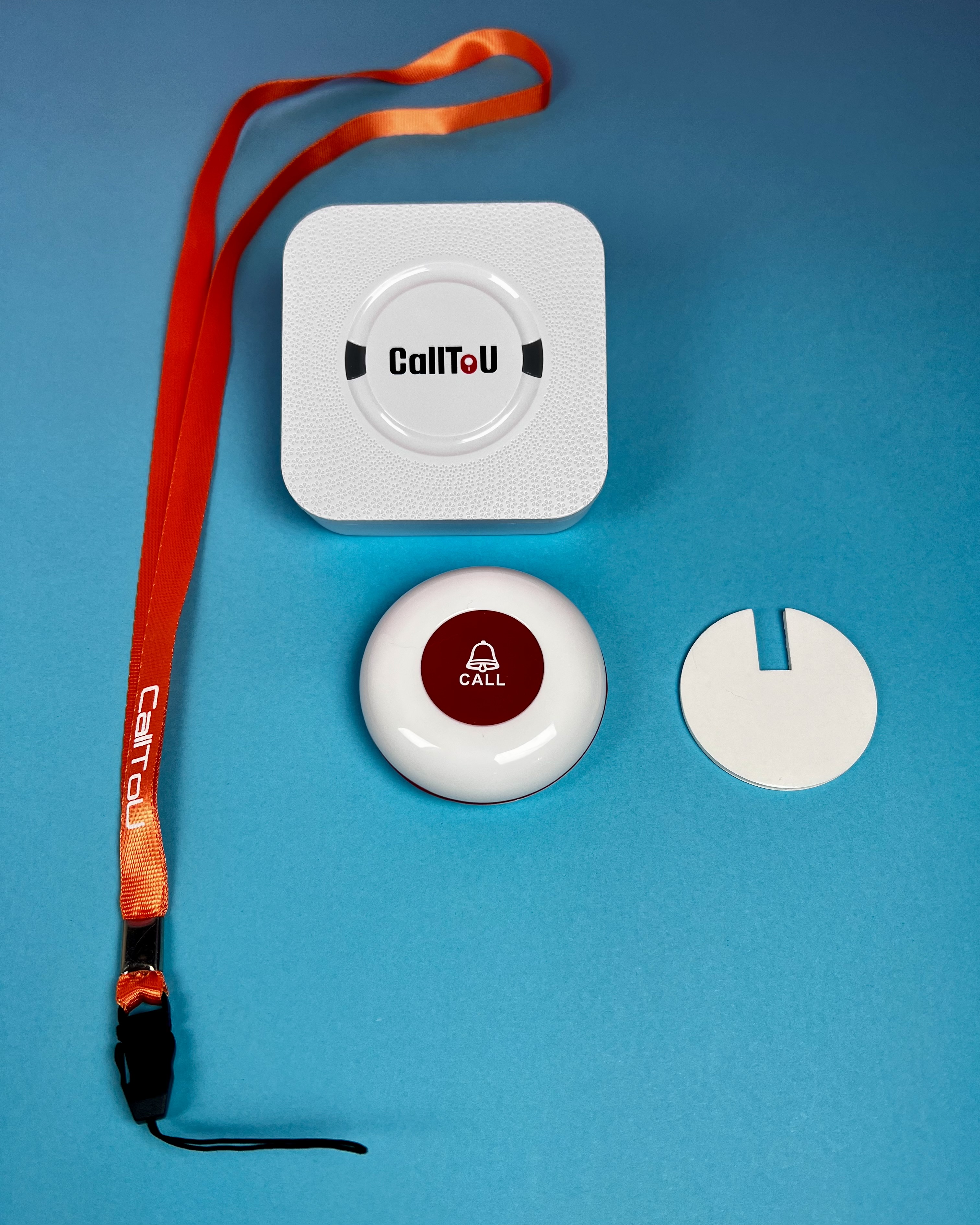 Wireless caregiver call button set with a white sounder, red lanyard, call button, and adhesive mounting pad. 