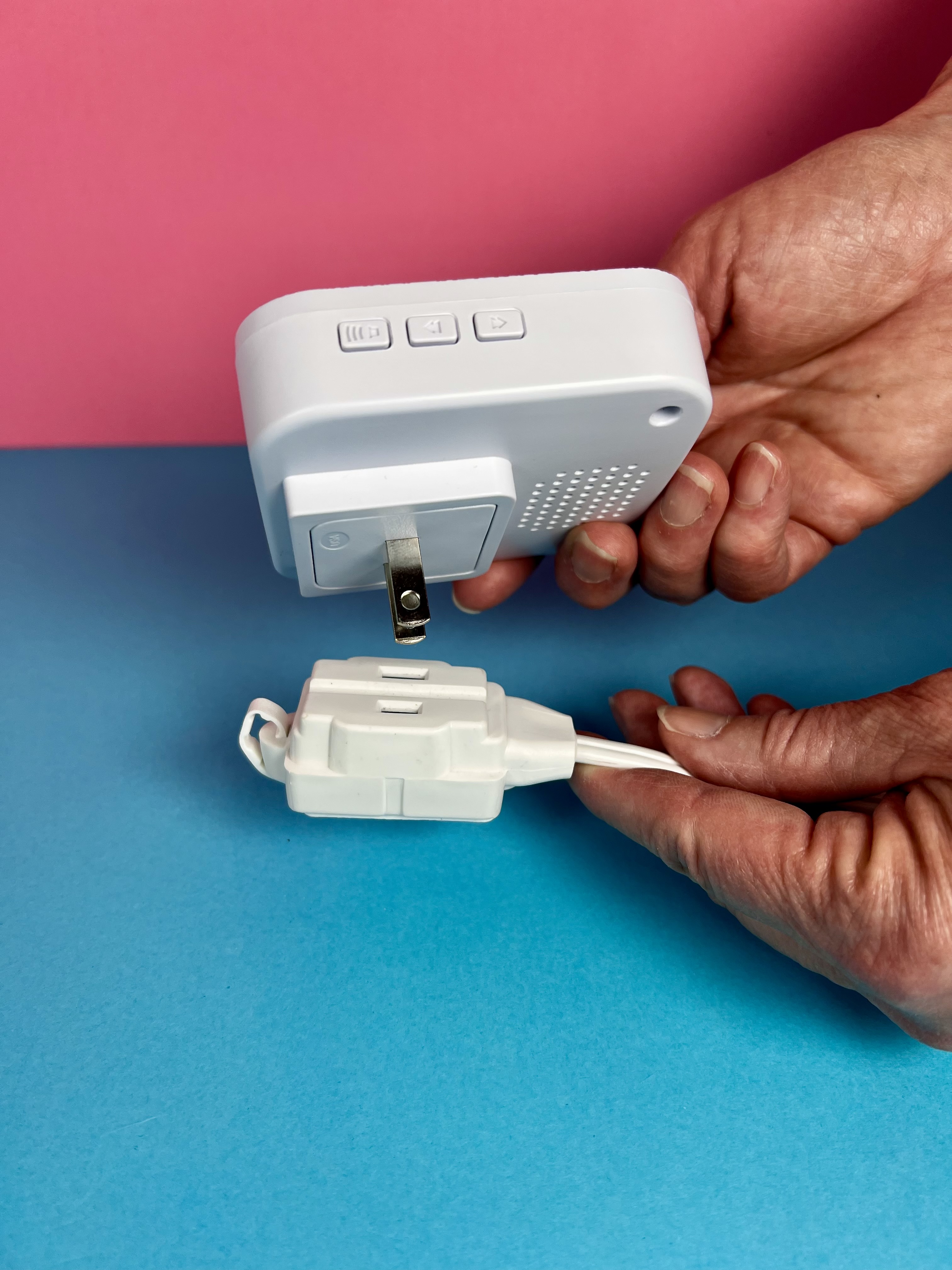 Hands holding the wireless caregiver alert sounder and call button to show how the pieces connect.