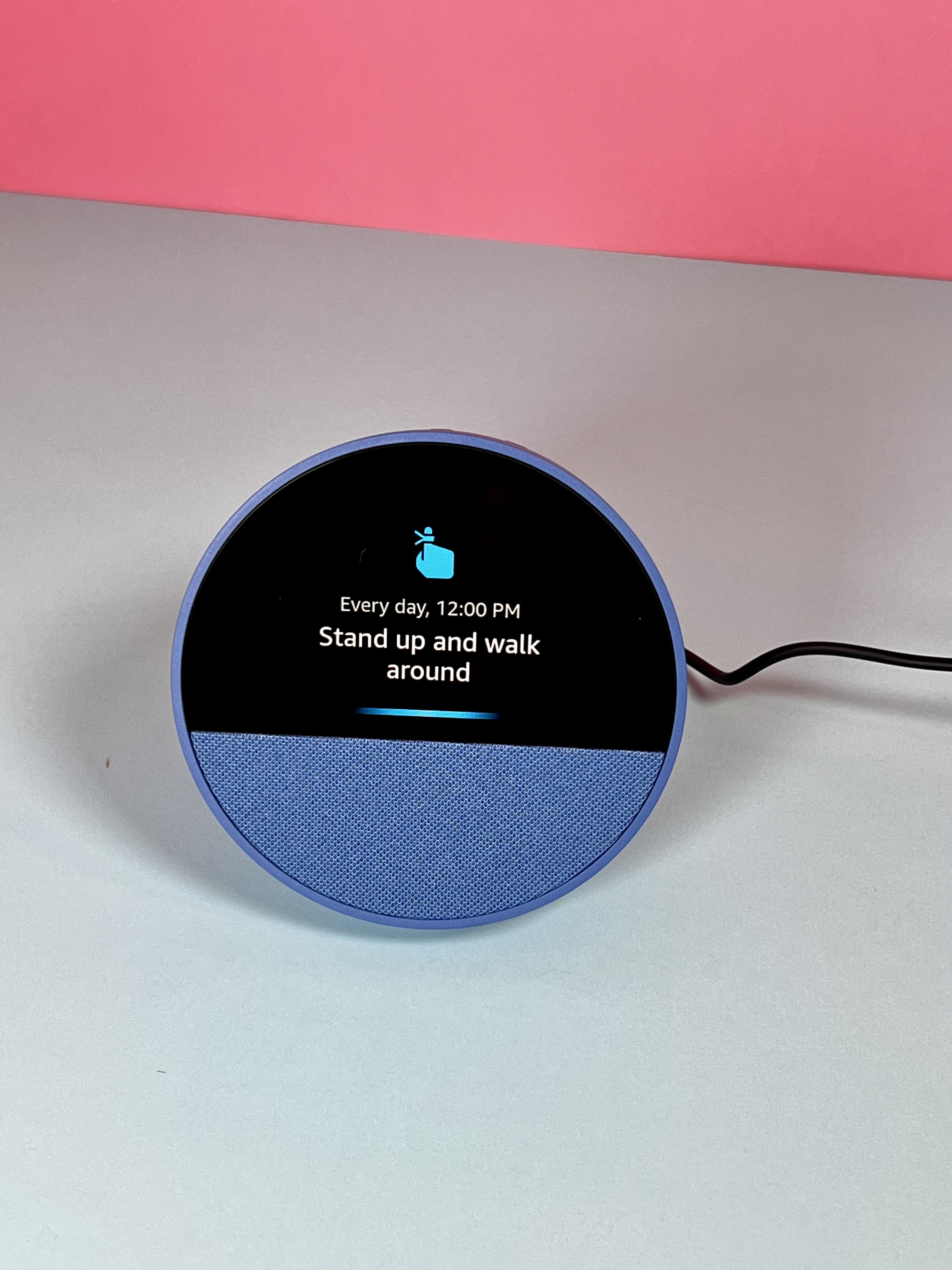 Alexa device with a screen showing a daily reminder to stand up and walk around at noon.