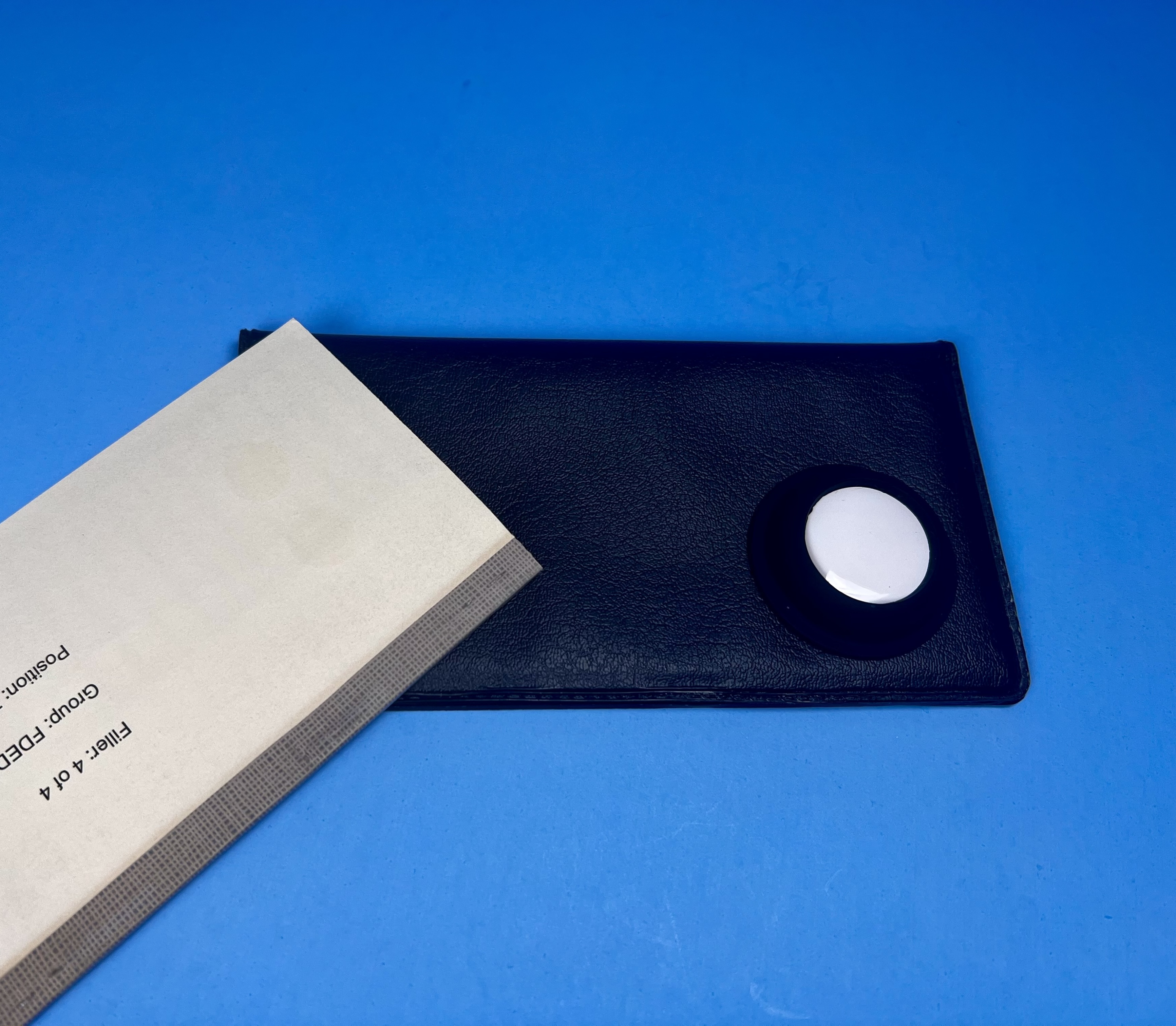 AirTag in an adhesive holder attached to a checkbook beside a receipt.