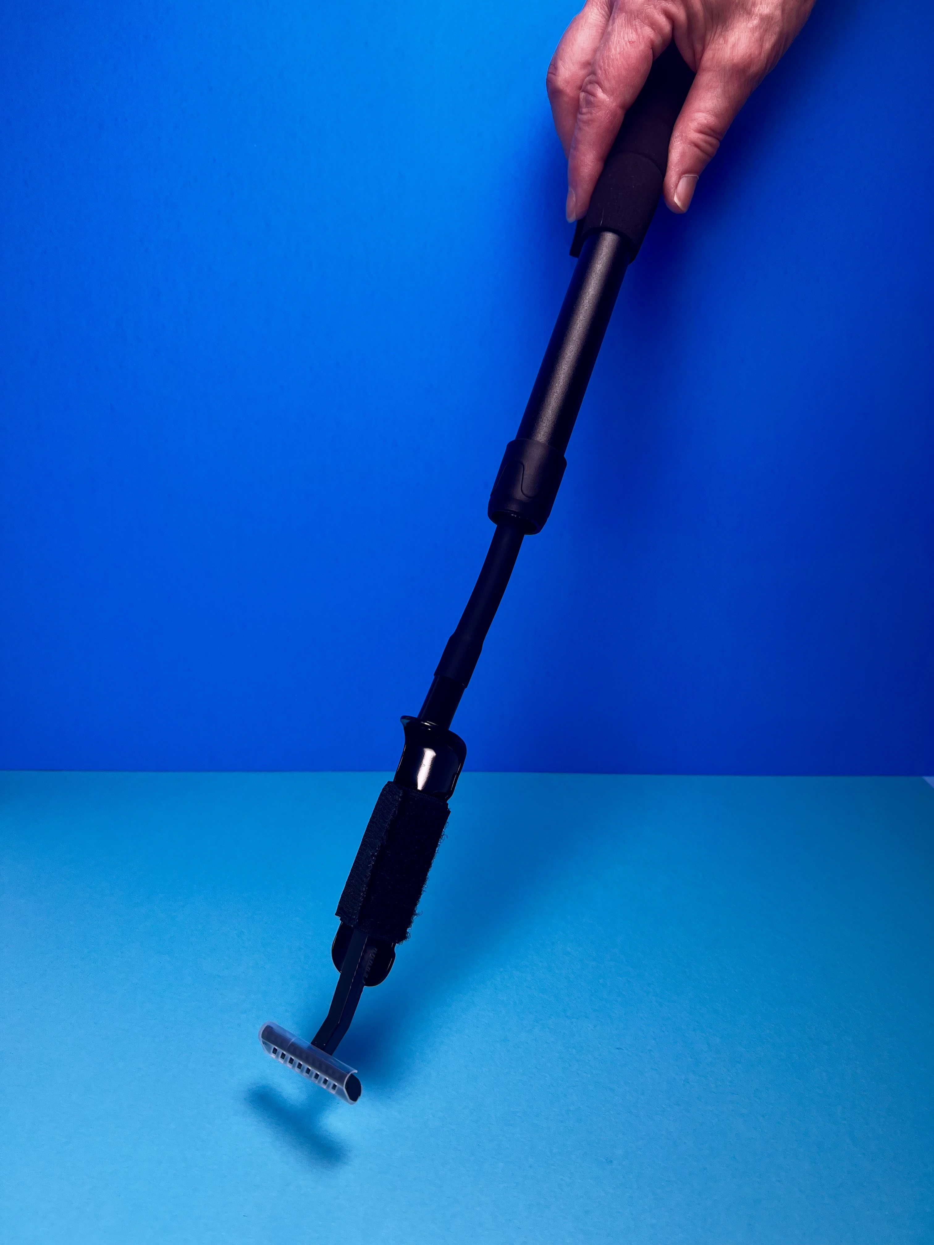 Person holding a thick weighted pen over a blue writing surface.