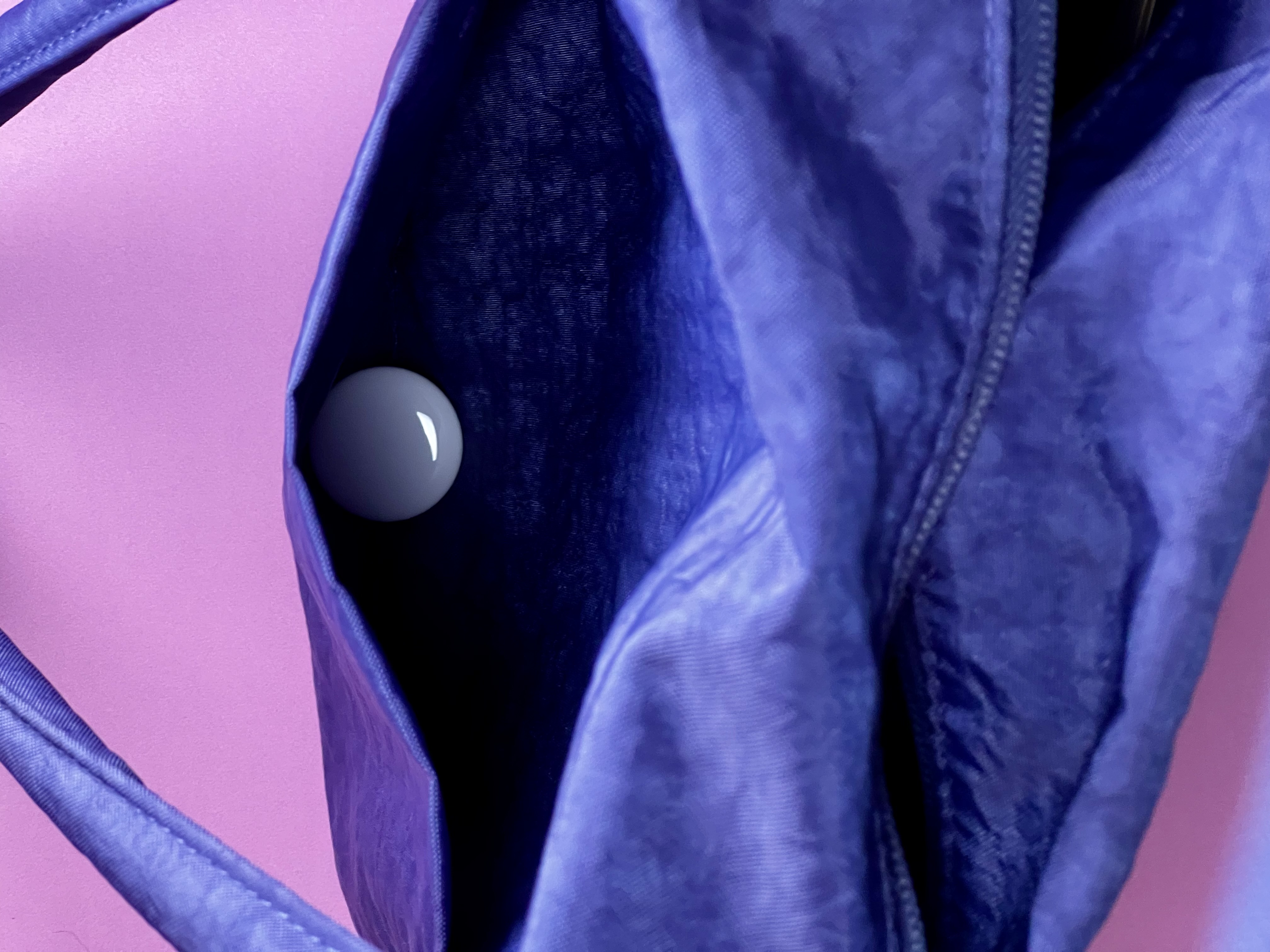 White AirTag placed inside an interior pocket of a blue bag.